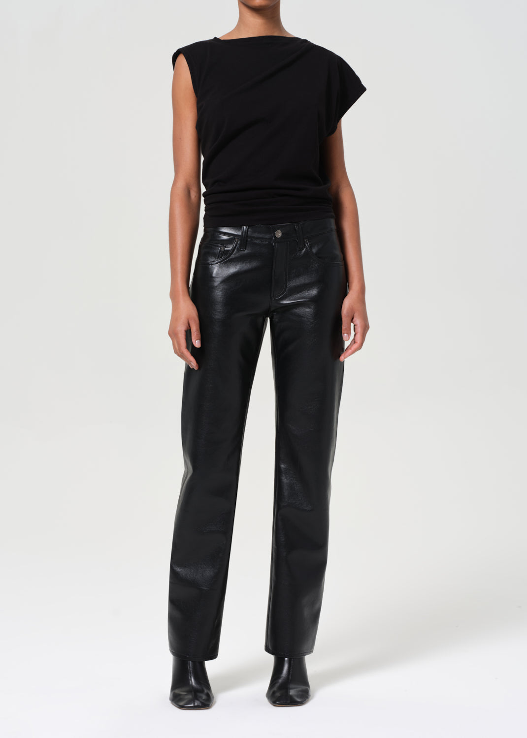 Person wearing a black sleeveless top and leather pants on a white background