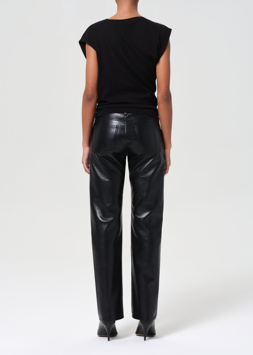 Person wearing black leather pants and a black top on a white background