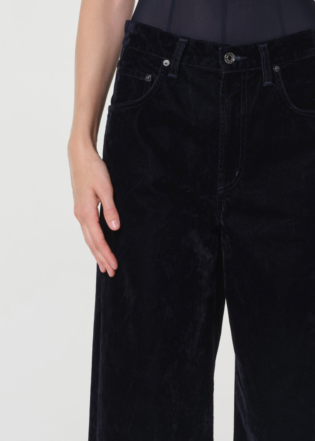 Blue velvet pants worn by a person on a white background