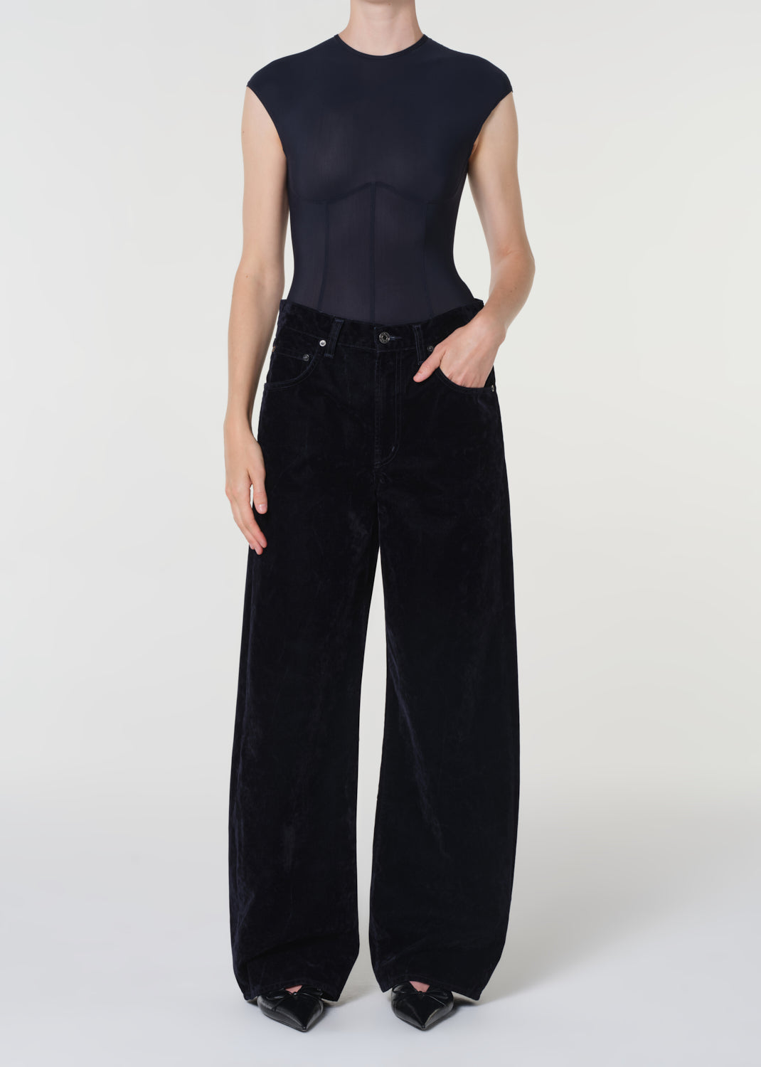 Person wearing a black sleeveless top and wide-leg pants on a white background