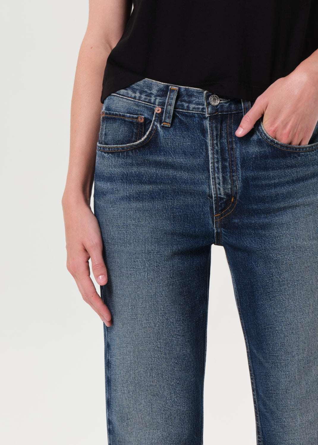 Person wearing blue jeans with a plain background