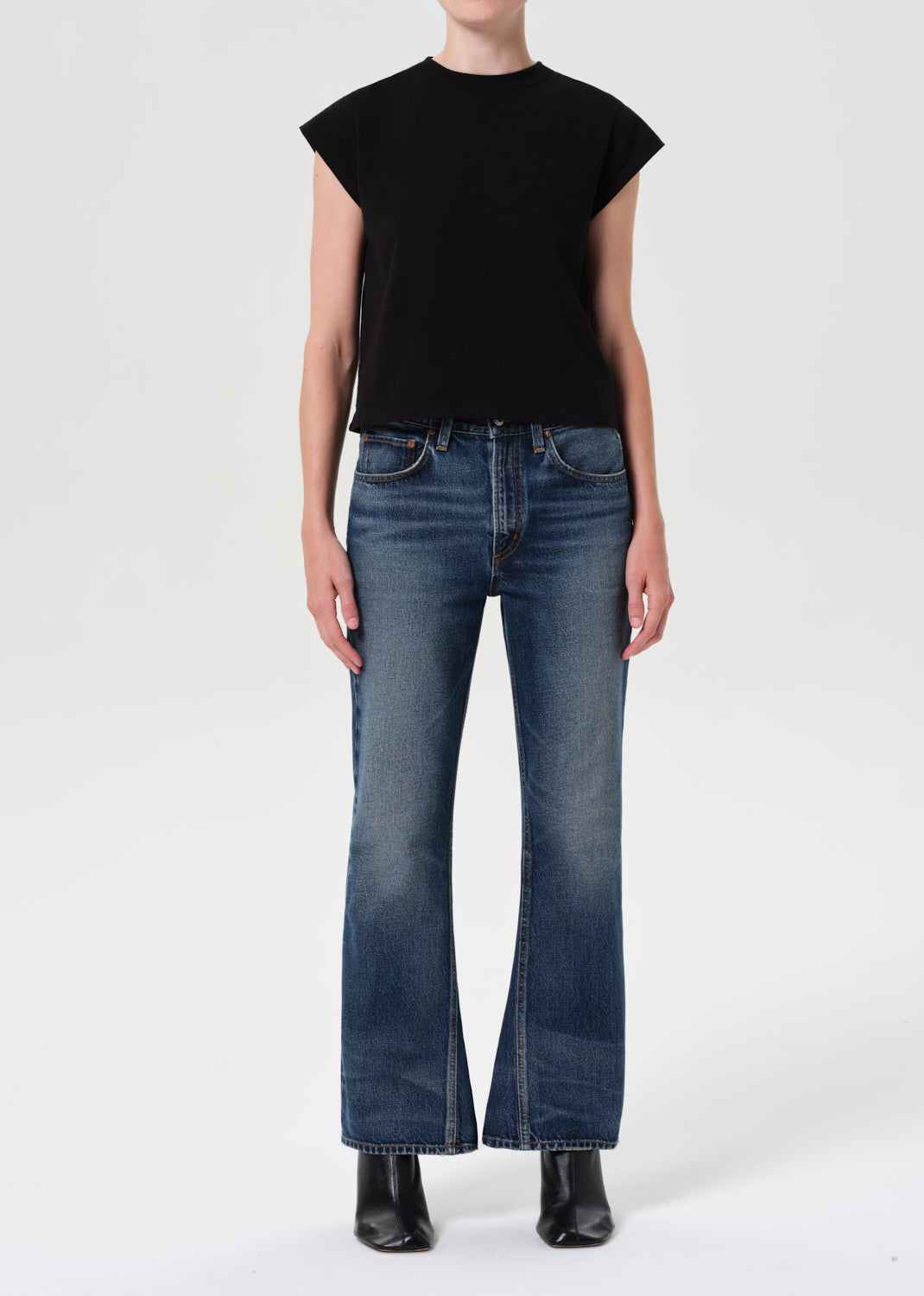 Person wearing a black top and blue jeans on a white background