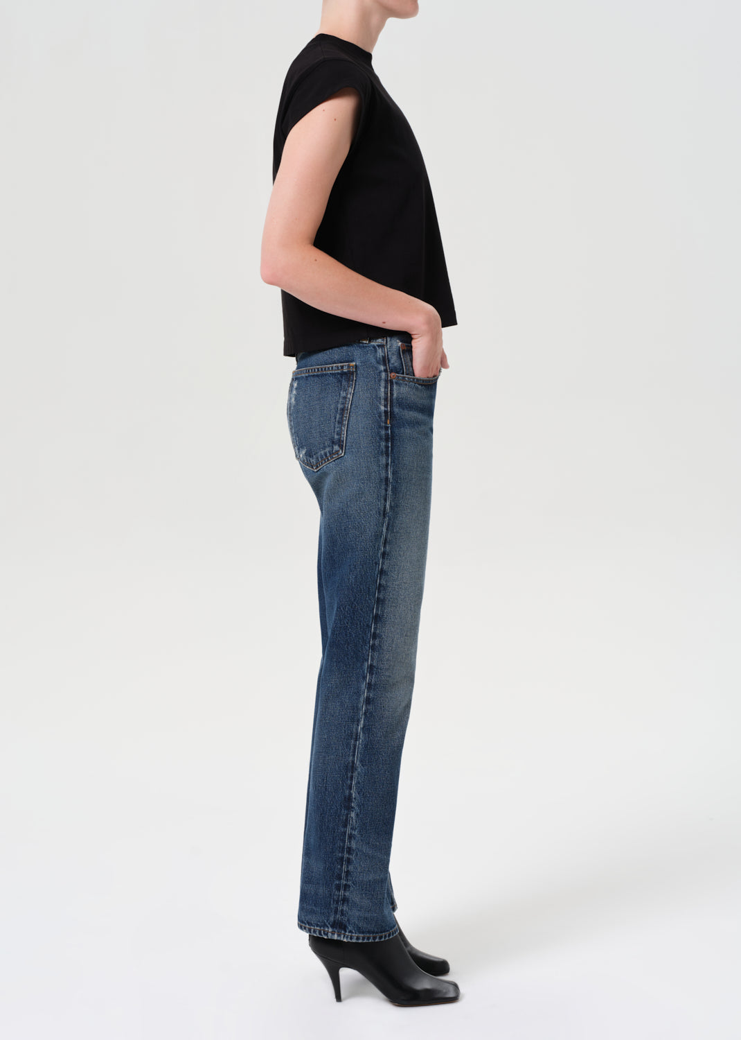 Person wearing blue jeans and a black top on a white background