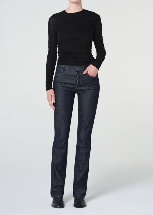 Person wearing a black long-sleeve top and dark jeans on a white background