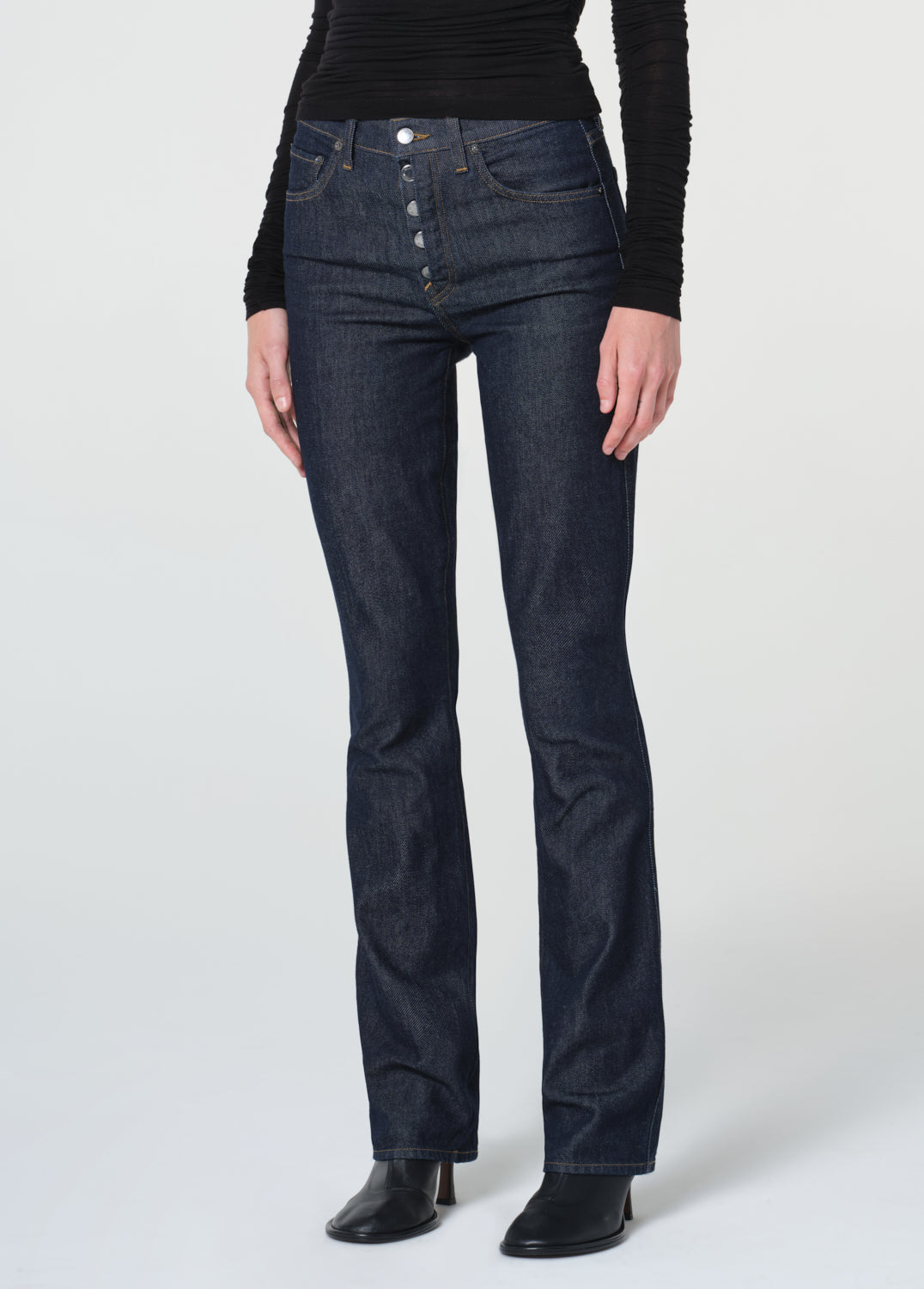 Person wearing dark blue jeans and a black top on a white background