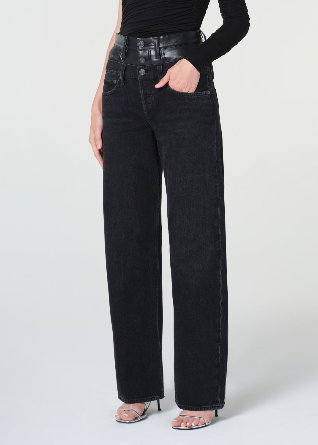 Person wearing black high-waisted jeans on a white background