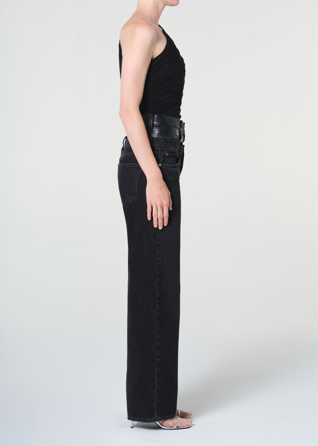 Person wearing black flared jeans and a black top on a white background