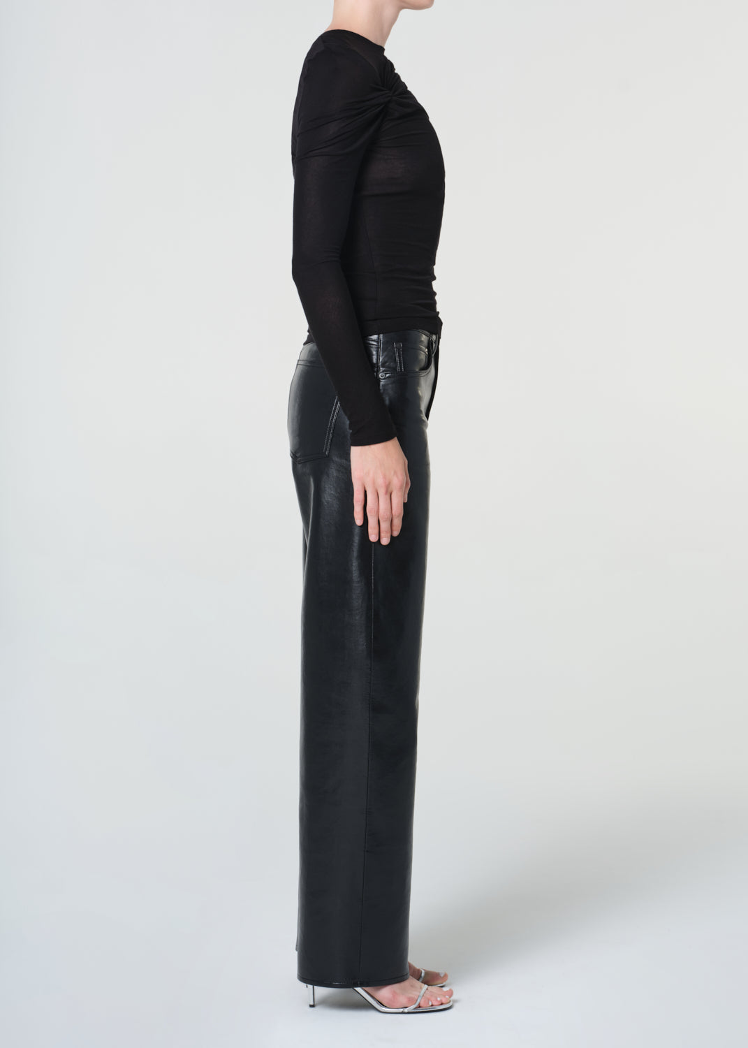 Person wearing black leather pants and a black top on a white background