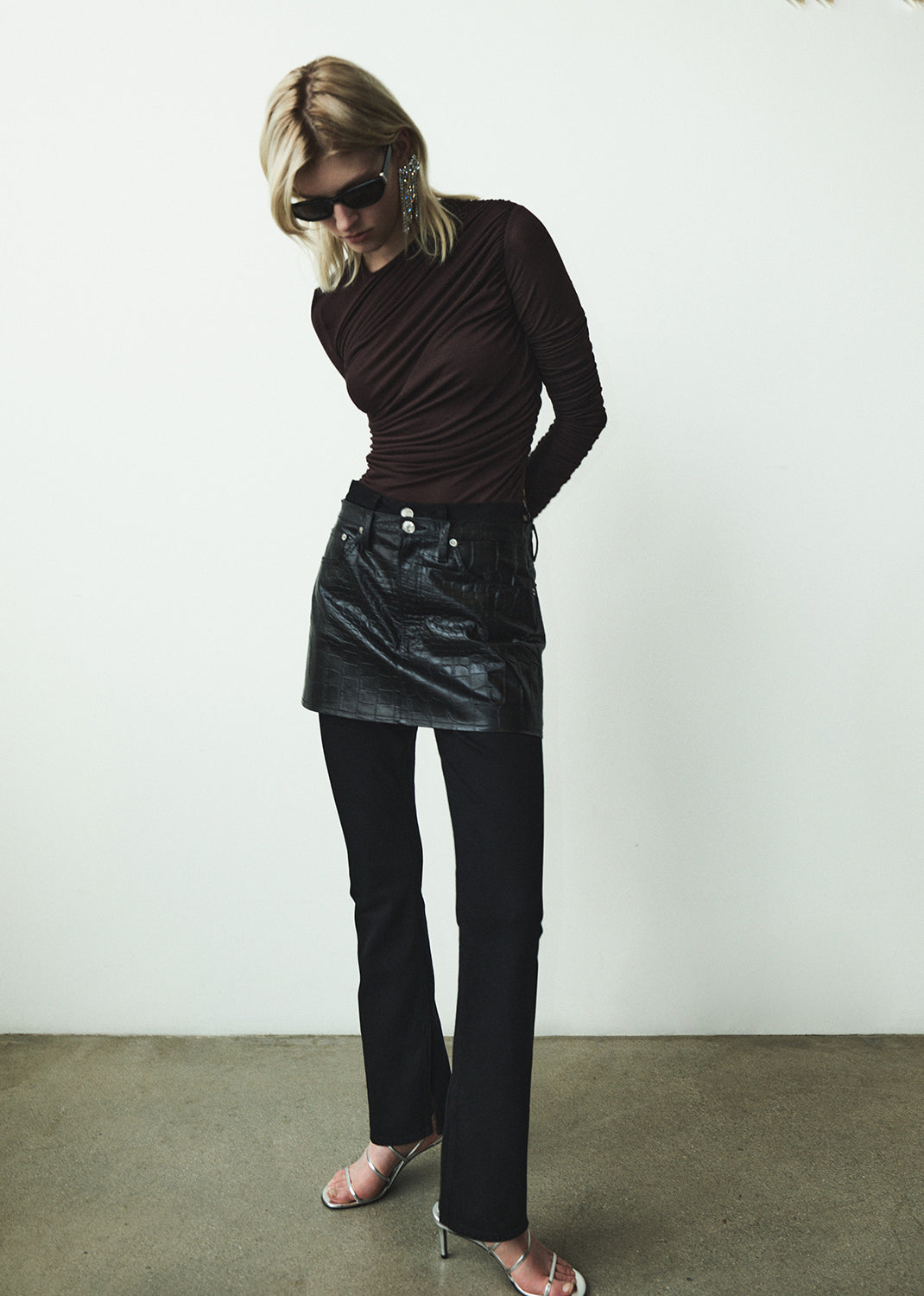 Woman wearing a brown top and black leather skirt against a white background