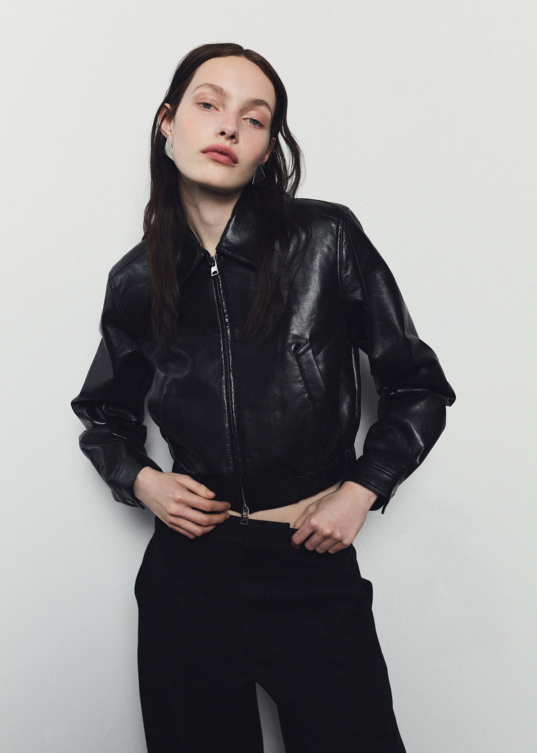 Person wearing a black leather jacket against a white background