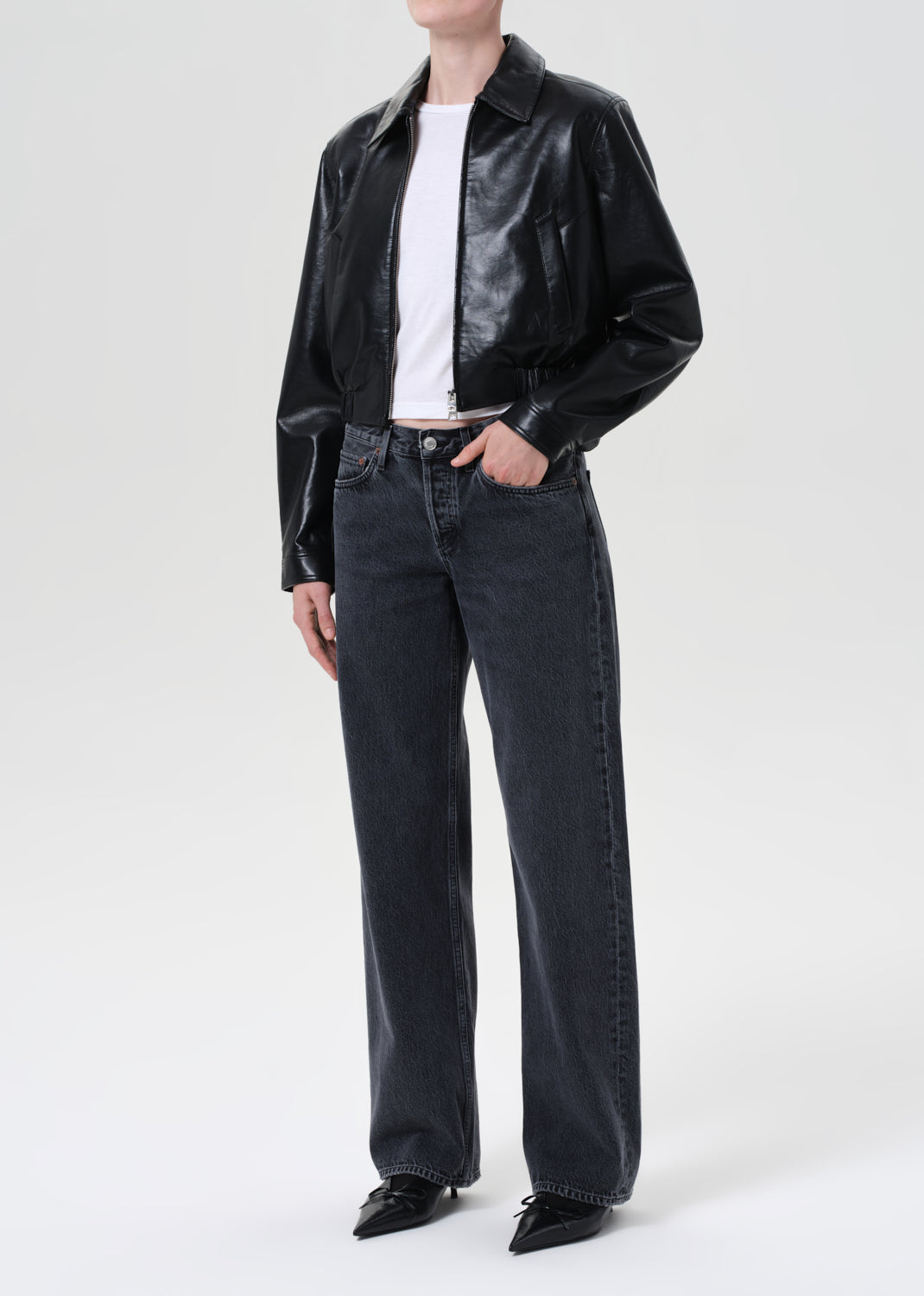 Person wearing a black leather jacket and dark jeans on a white background