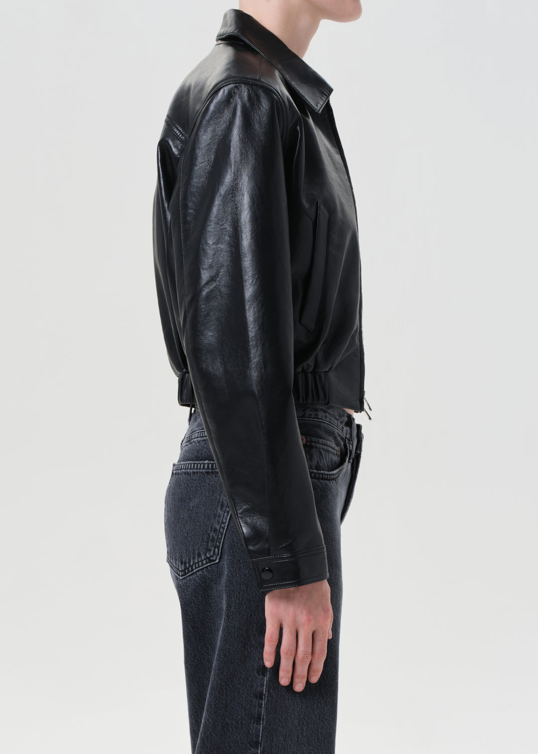 Person wearing a black leather jacket and jeans on a white background