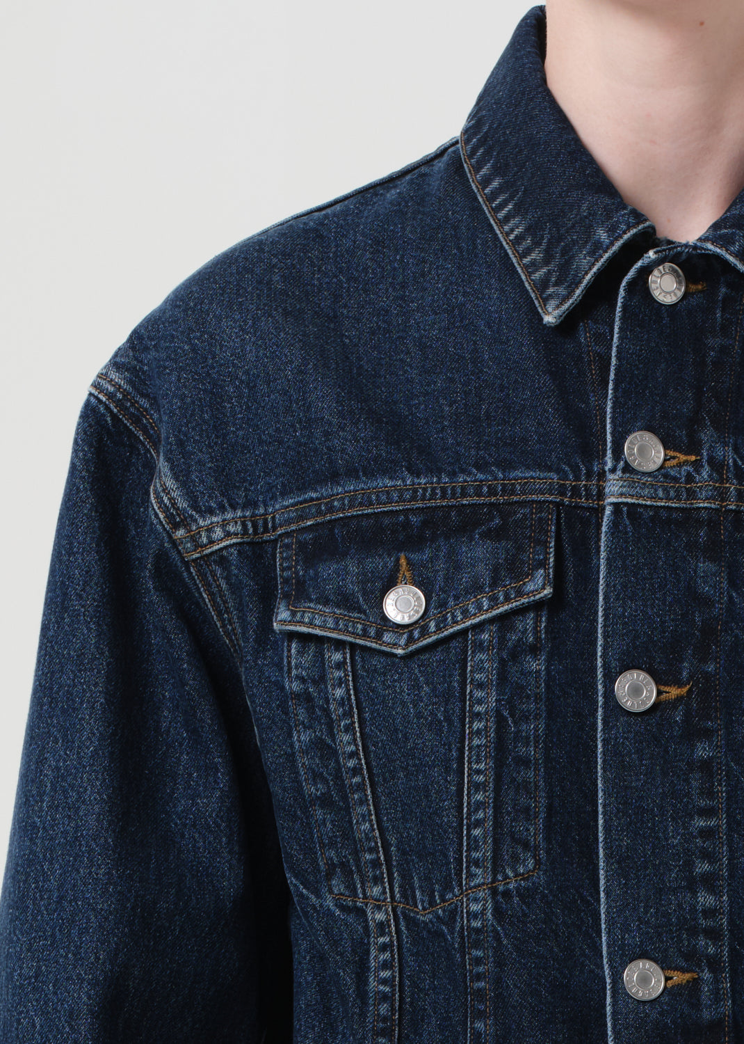 Close-up of a blue denim jacket with buttons on a light gray background