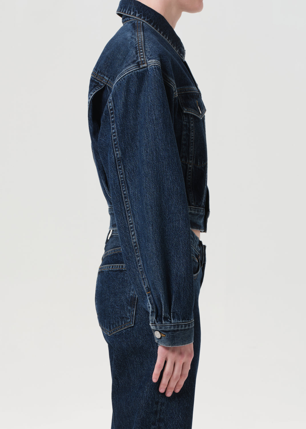 Person wearing a dark blue denim jacket on a white background