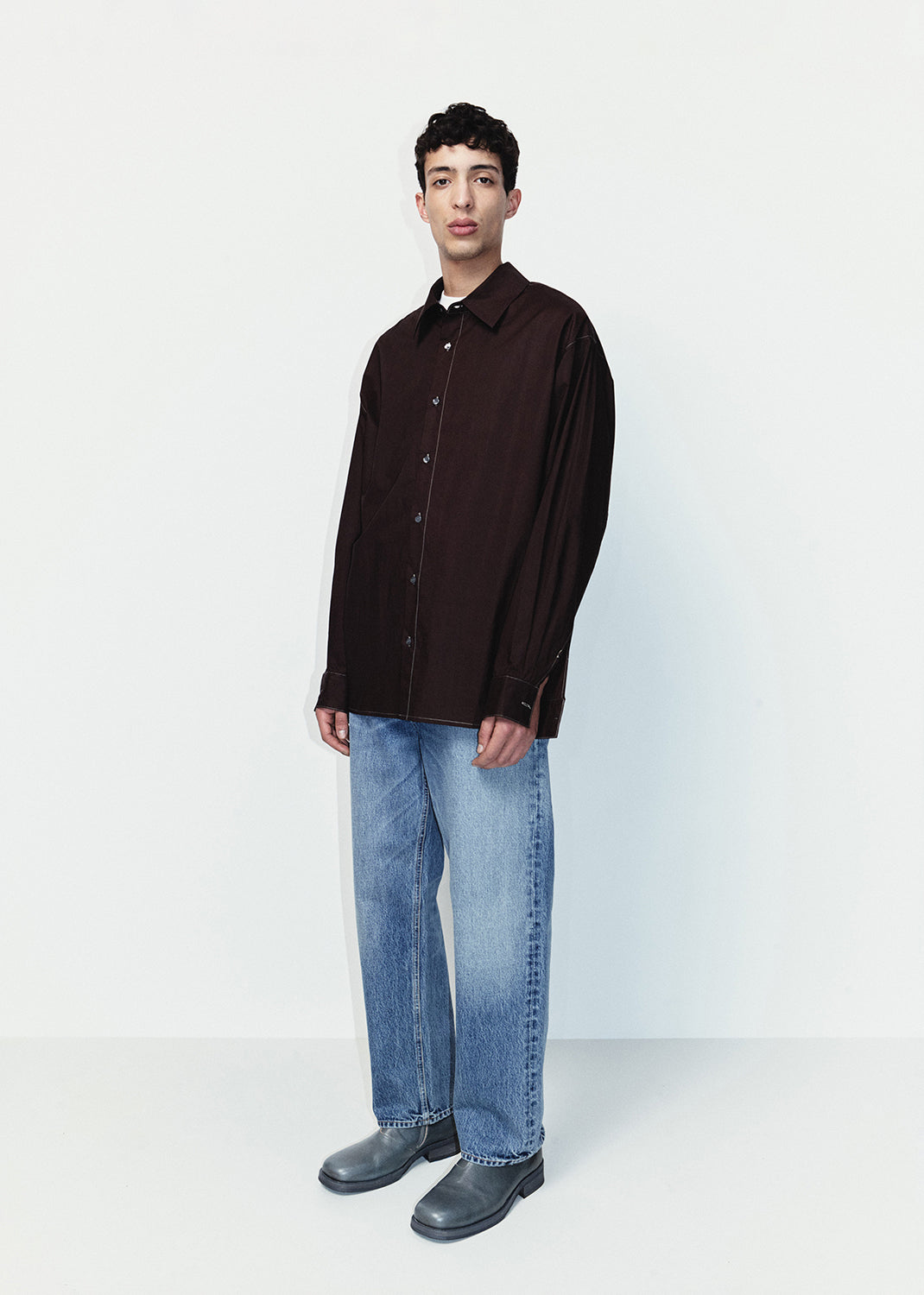 Person wearing a black shirt and blue jeans on a white background