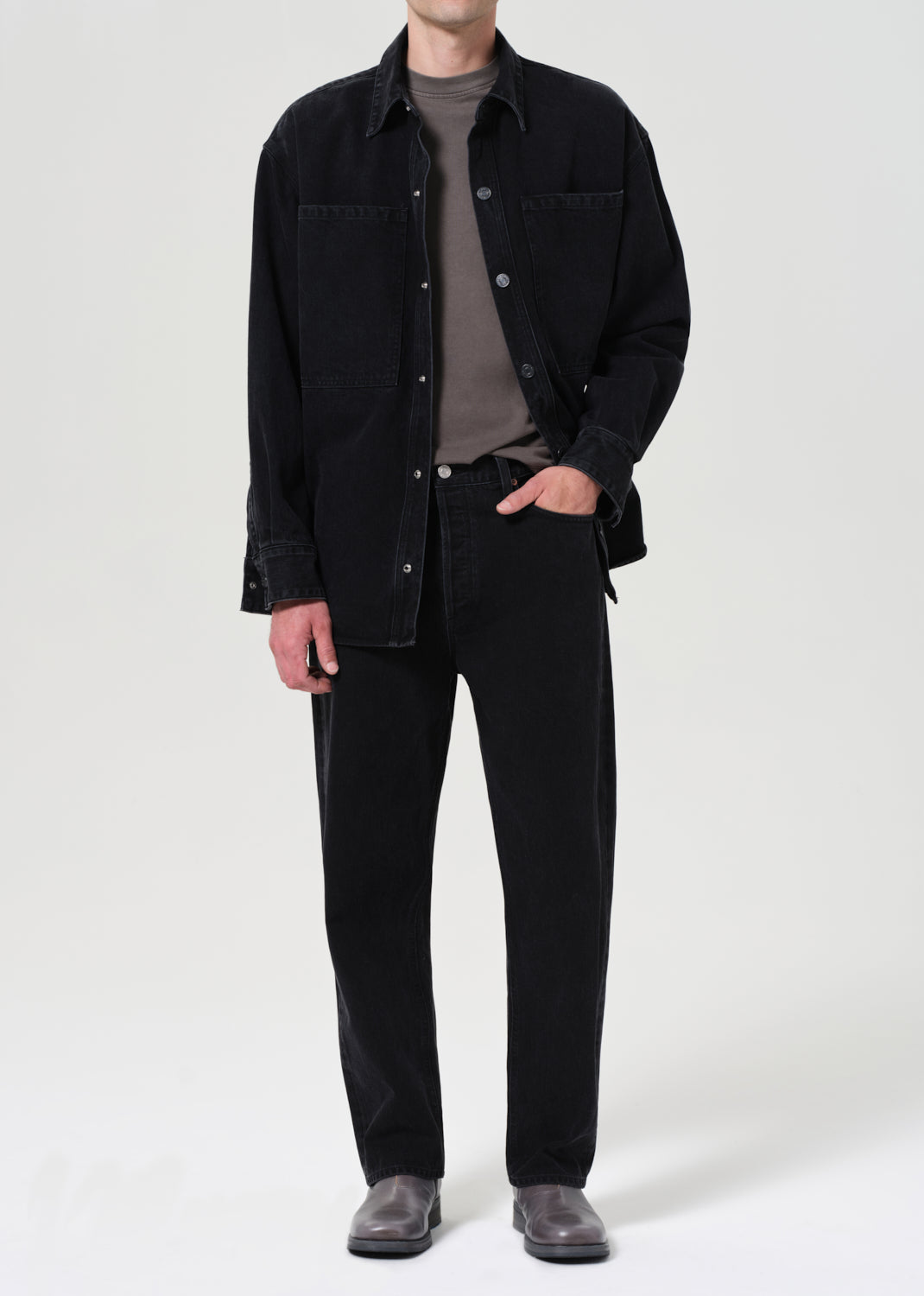 Person wearing a black shirt and pants on a white background