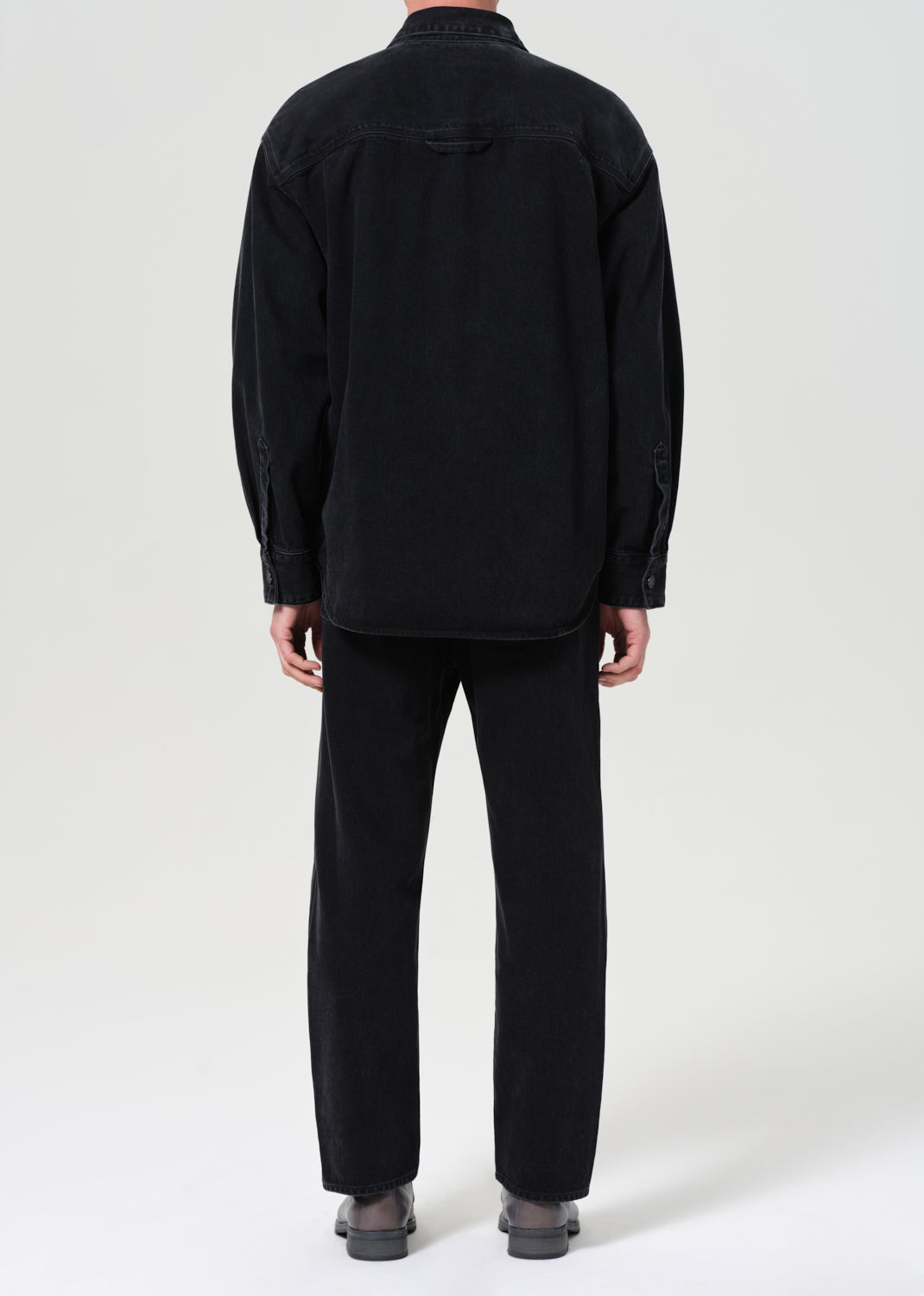 Person wearing a black jacket and pants on a white background