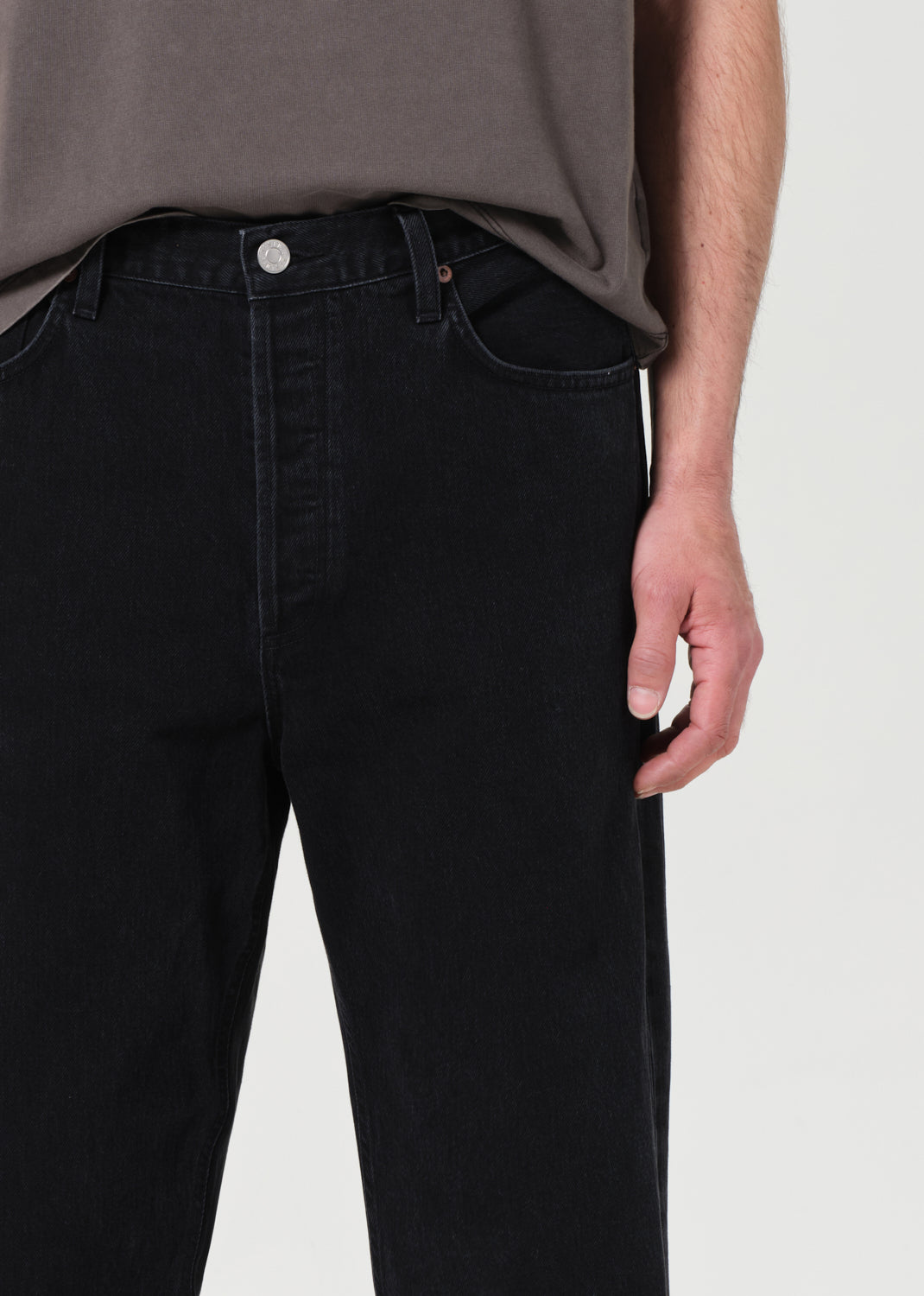 Person wearing black jeans and a gray shirt on a white background