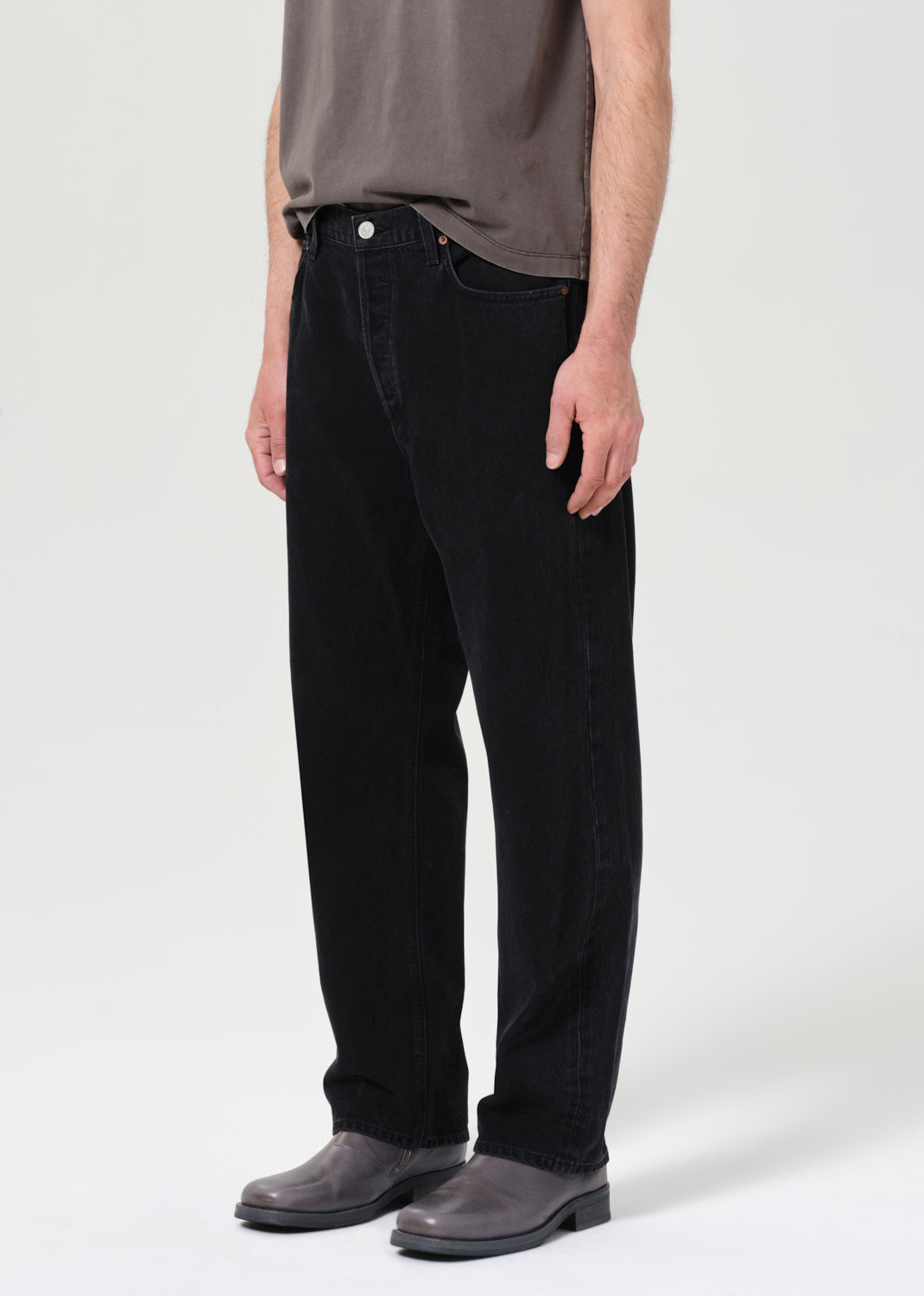 Person wearing black jeans and gray shoes on a white background