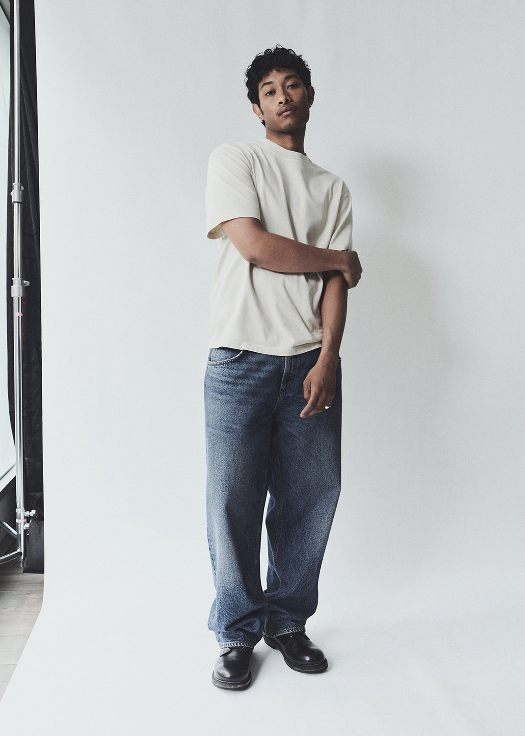 Person wearing a white t-shirt and blue jeans standing against a plain white background