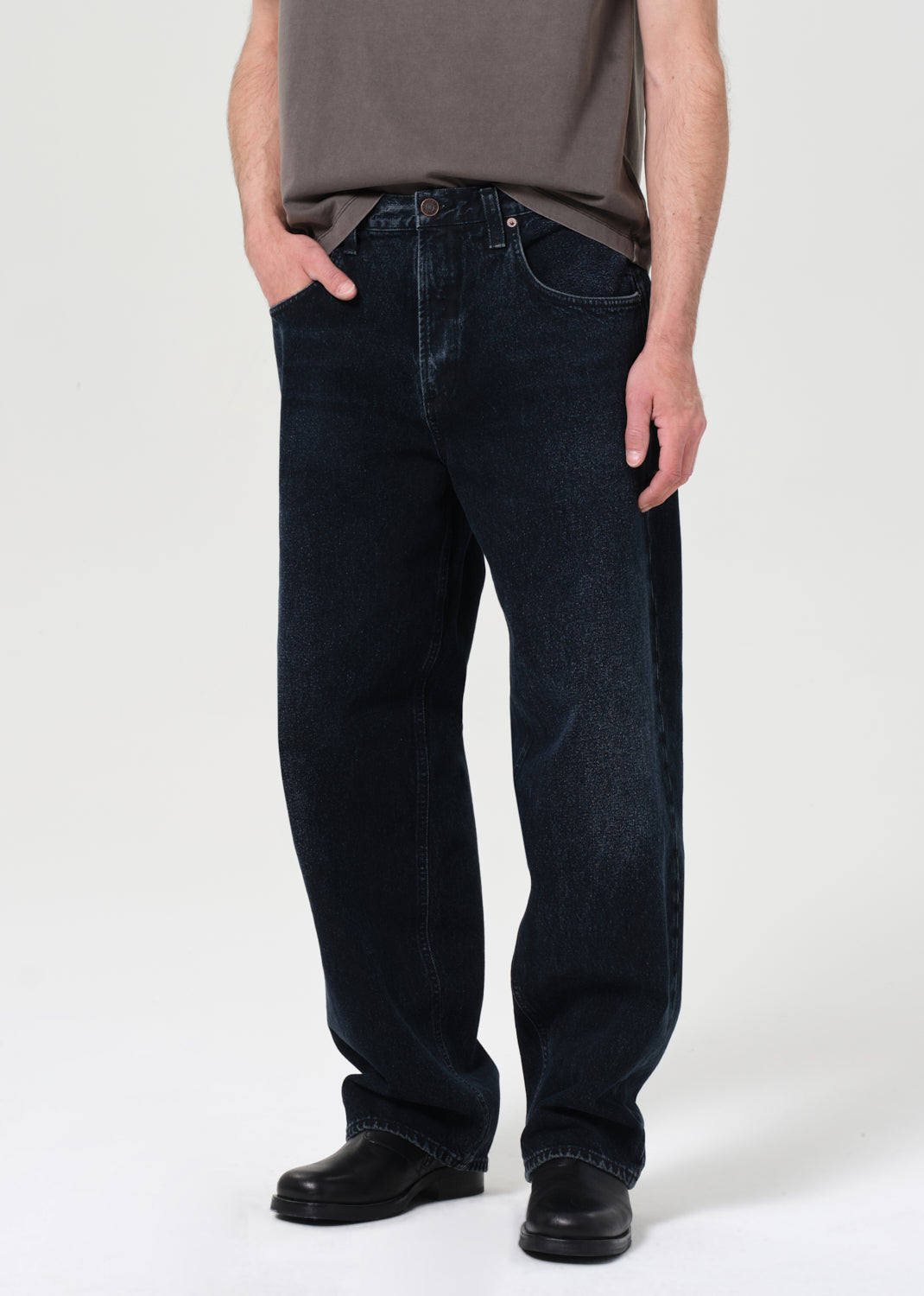 Person wearing dark blue jeans and a gray shirt on a white background