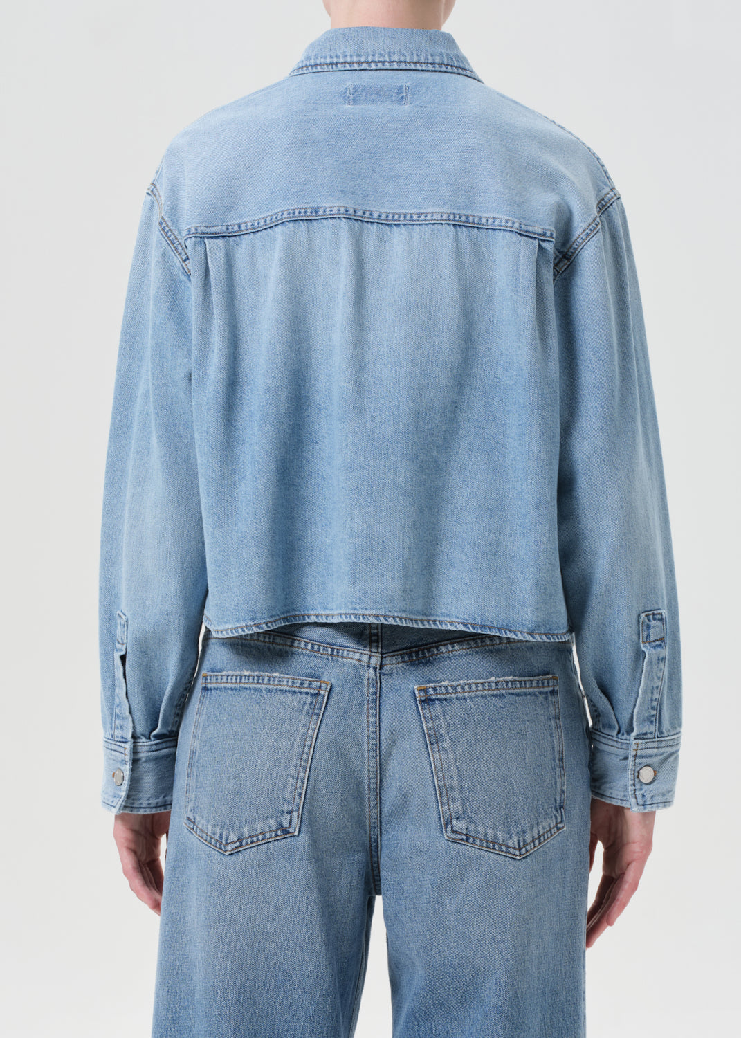 Light blue denim jacket and jeans on a plain background