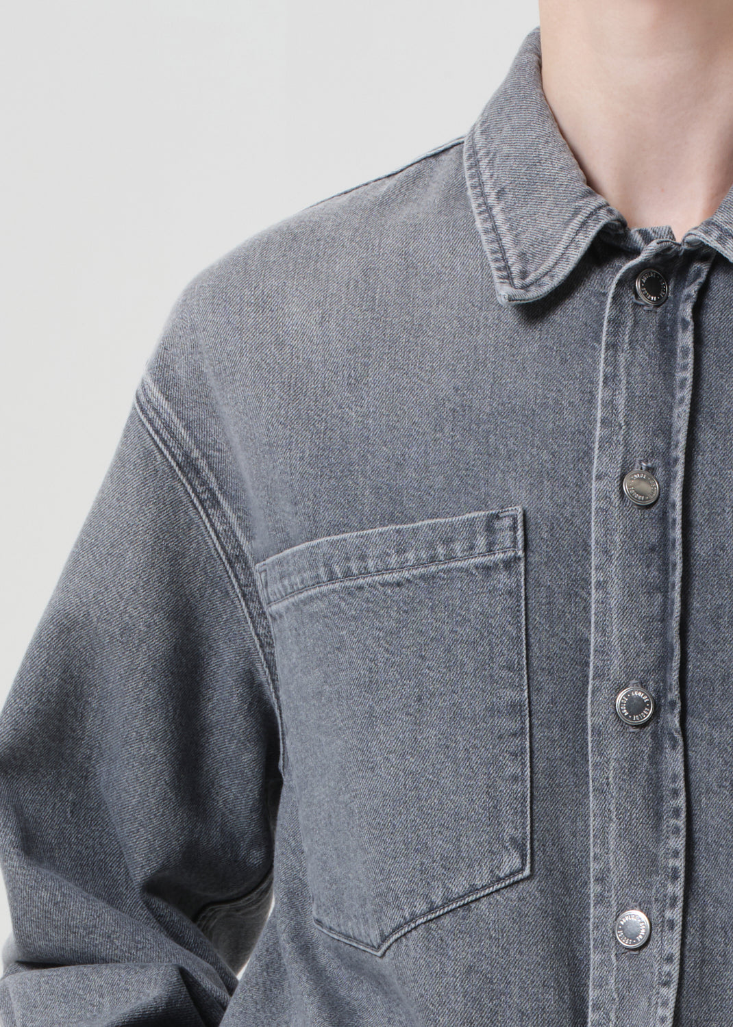 Close-up of a gray denim shirt with a collar on a light gray background