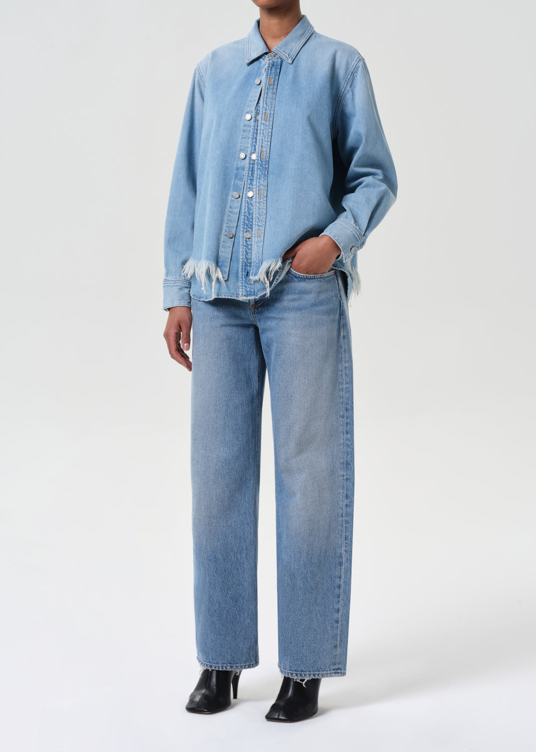 Person wearing a light blue denim jacket and jeans on a white background