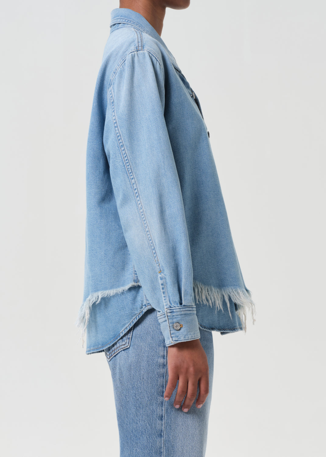 Light blue denim jacket with frayed hem on a plain background