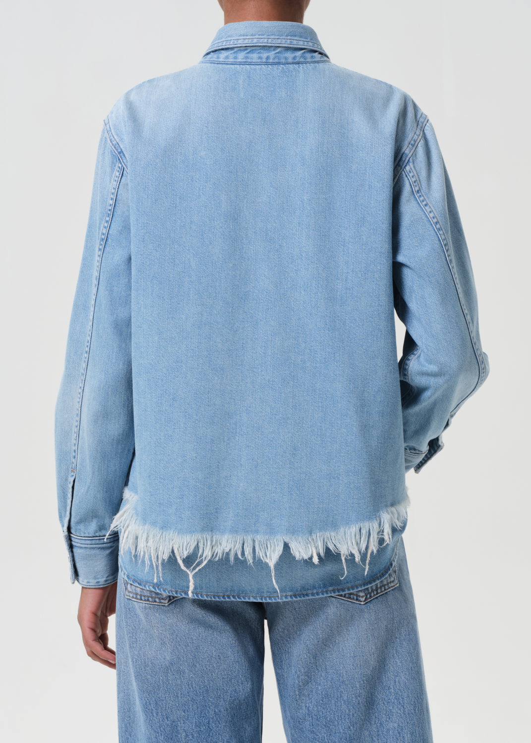 Light blue denim jacket with frayed hem on a plain background