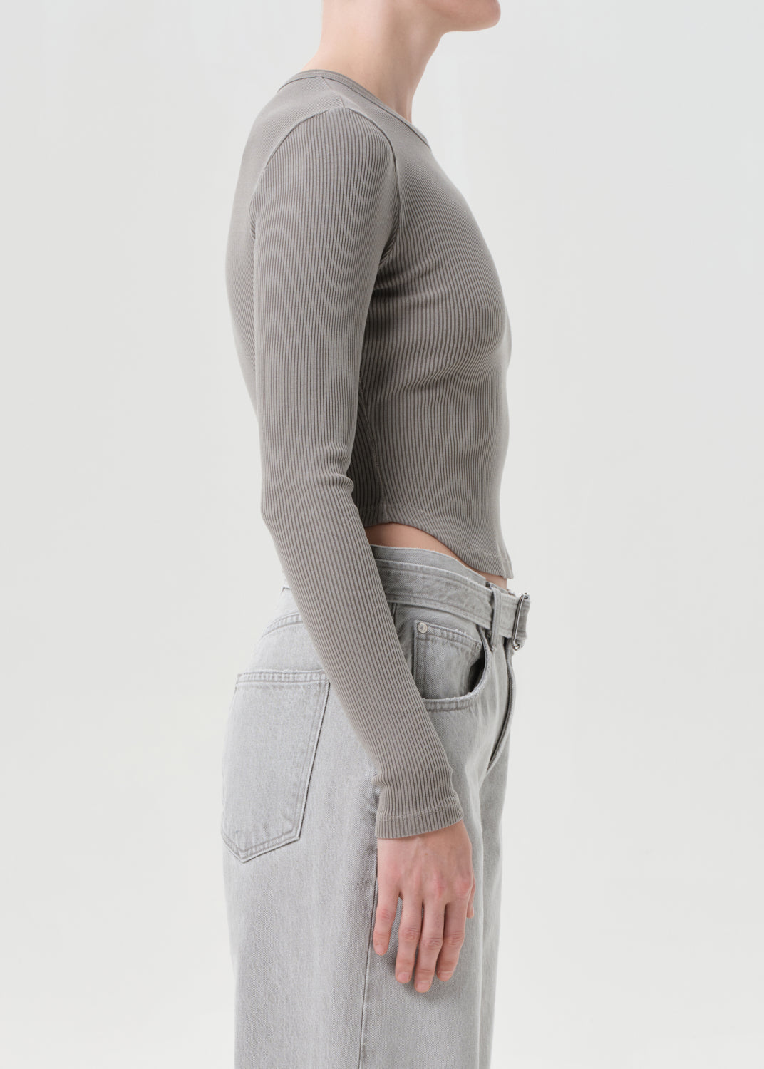 Person wearing a gray ribbed long-sleeve top and light gray jeans on a white background