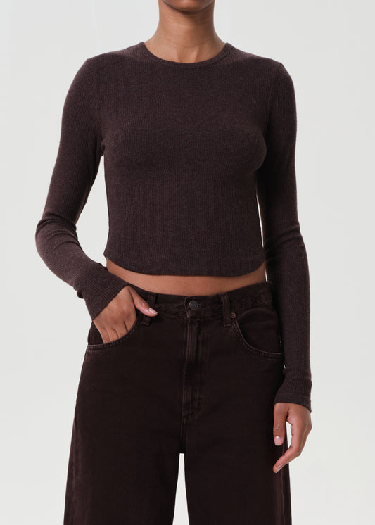 Person wearing a dark brown long-sleeve crop top and black high-waisted pants on a white background