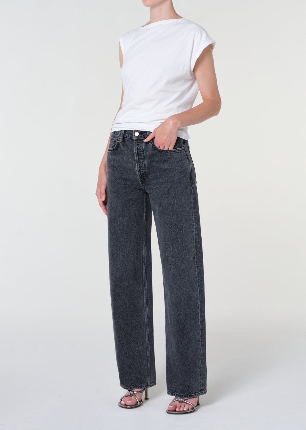 Person wearing a white t-shirt and dark jeans on a white background