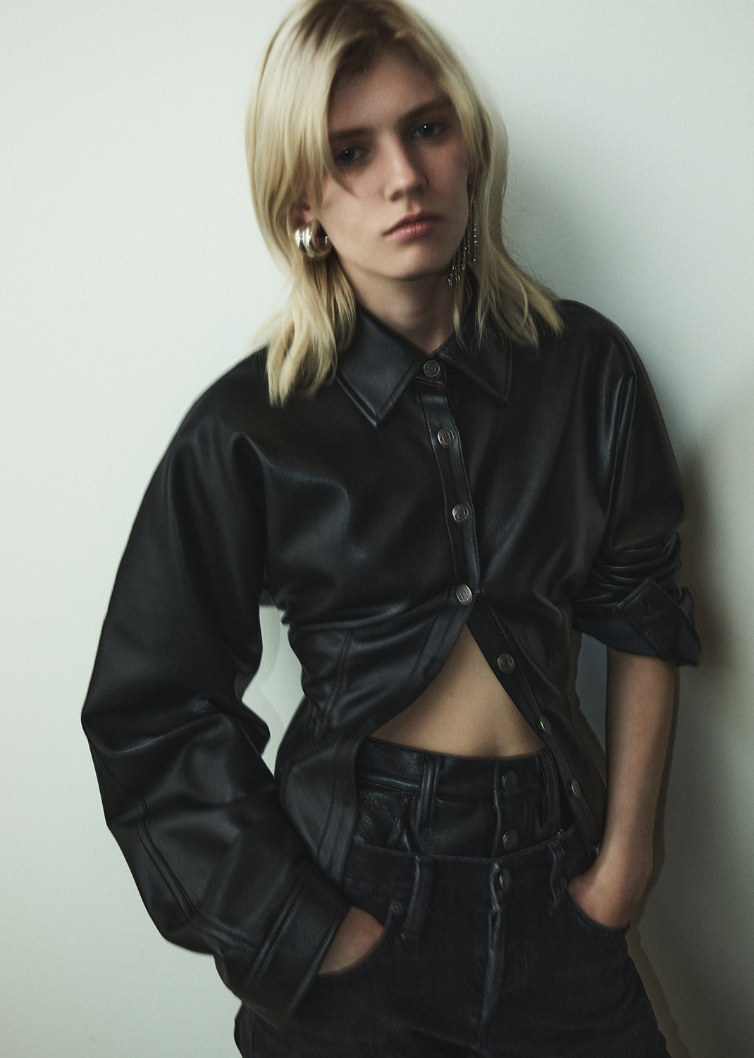 Person wearing a black leather jacket against a plain background