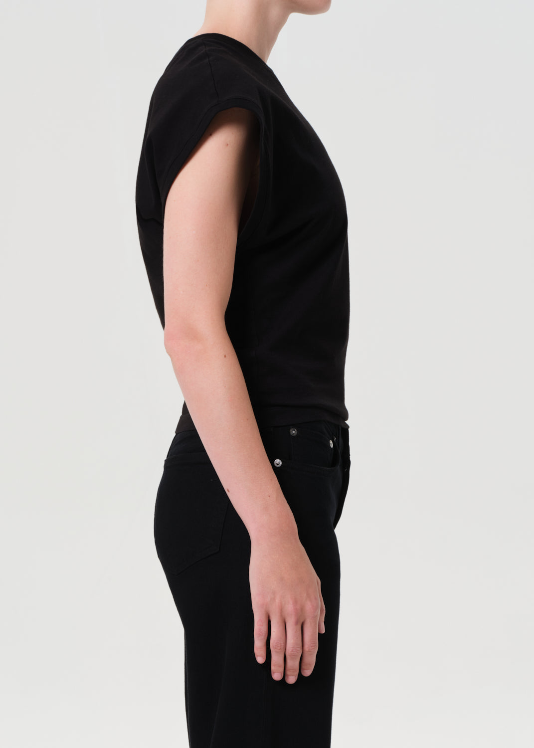 Person wearing a black sleeveless top and pants on a light gray background