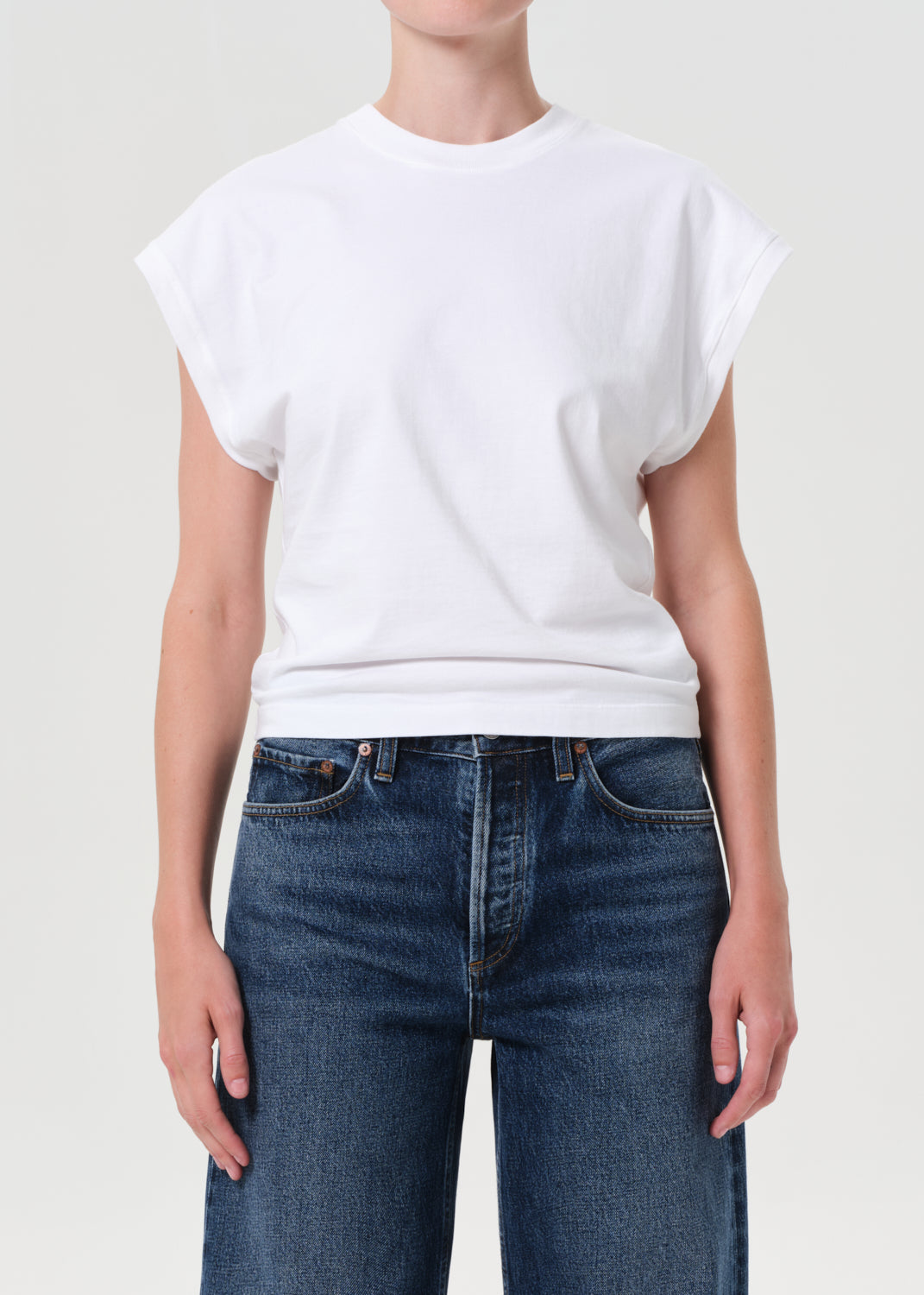 Person wearing a white t-shirt and blue jeans on a plain background
