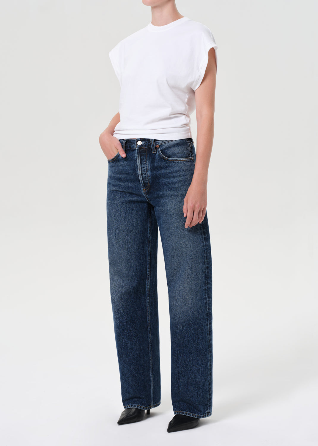 Person wearing blue jeans and a white top on a white background