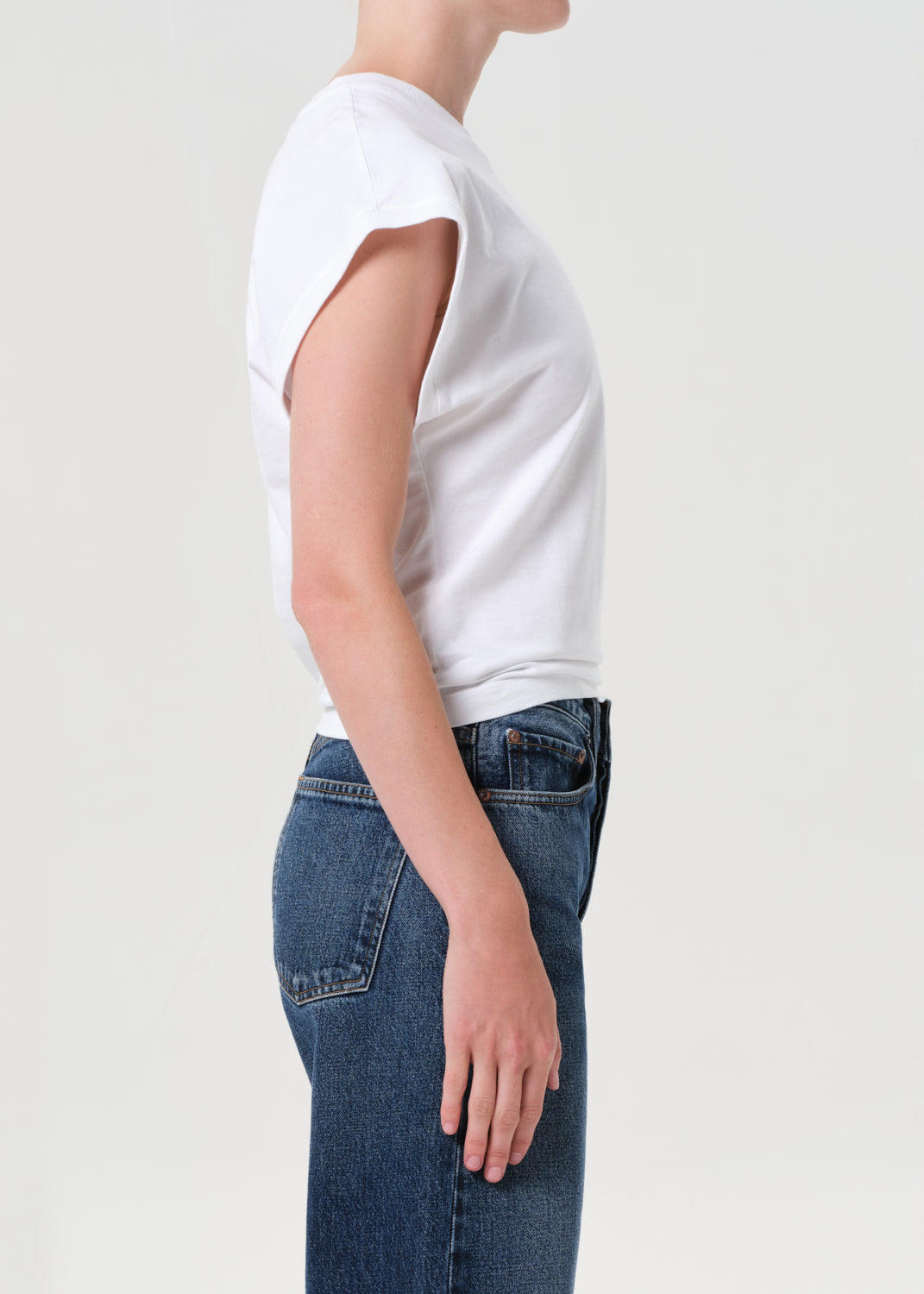 Person wearing a white t-shirt and blue jeans on a light gray background
