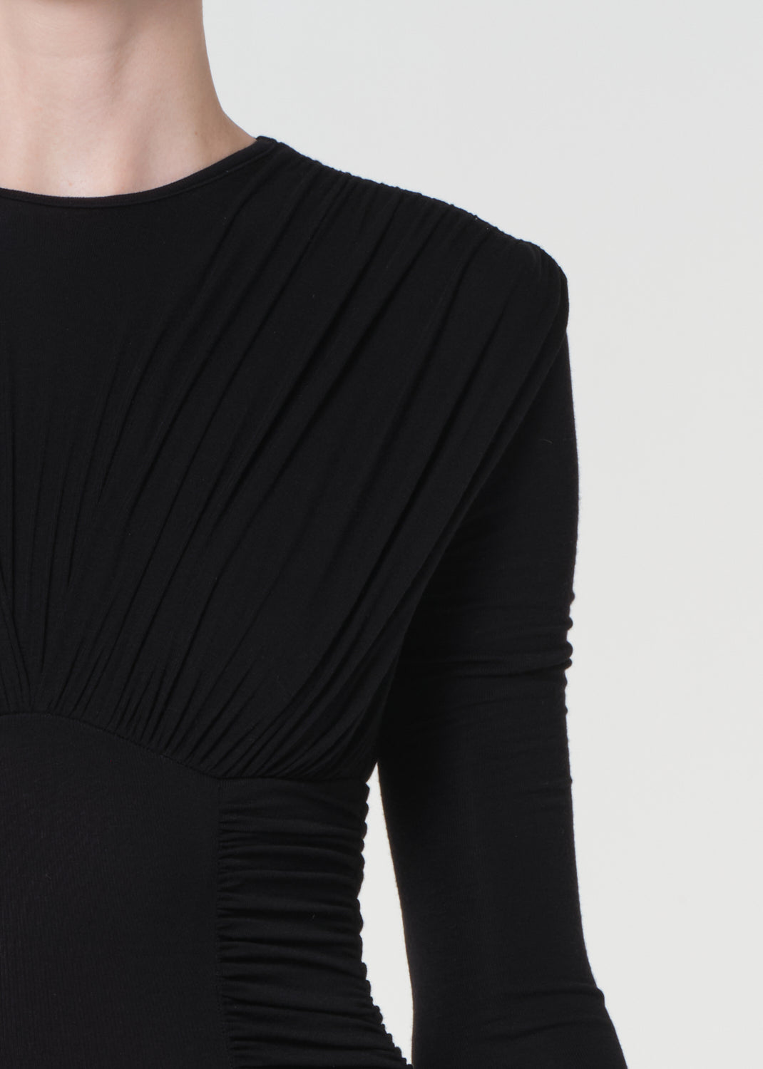 Black long-sleeve dress with draped design on a white background