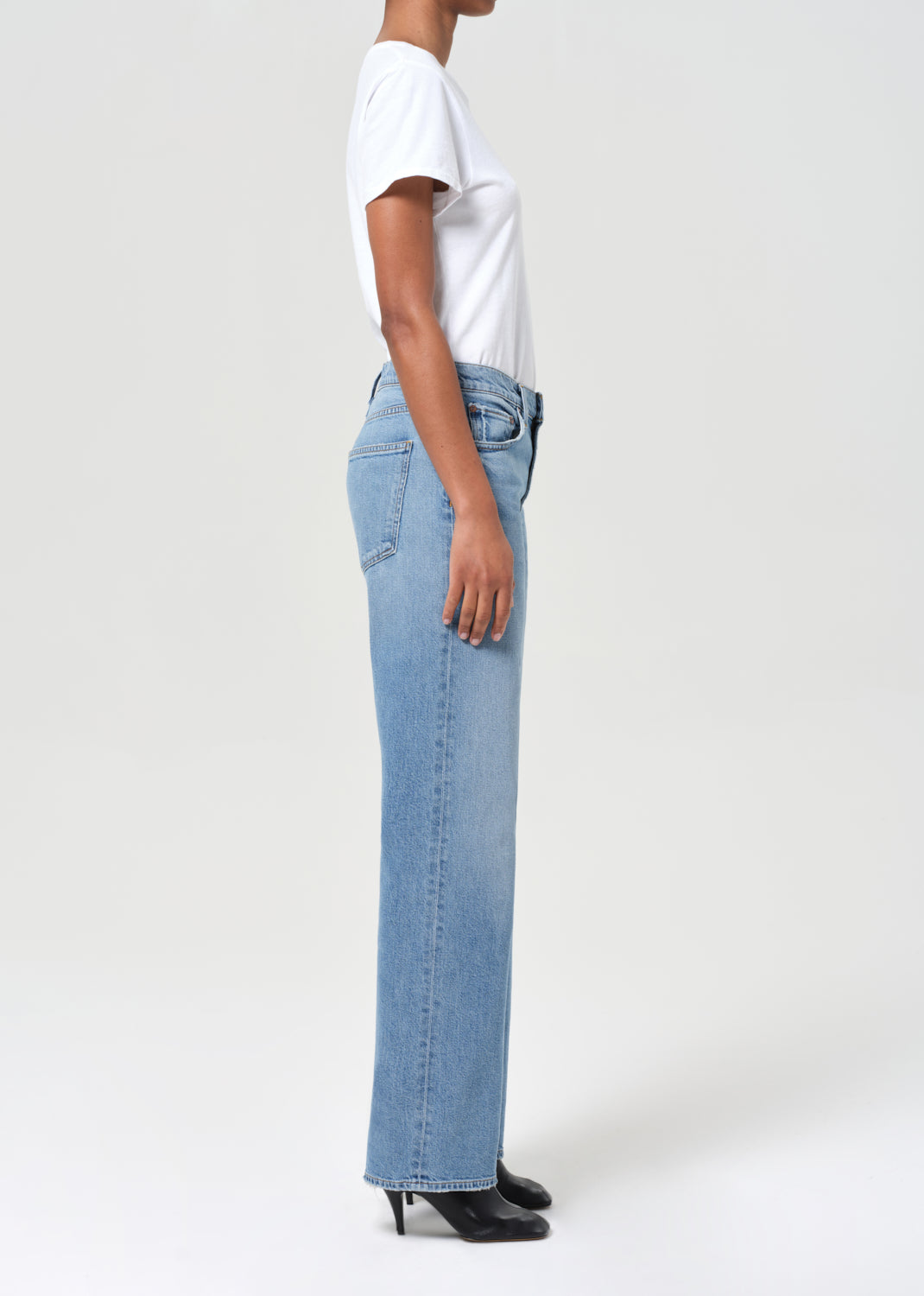 Person wearing light blue jeans and a white shirt on a plain background