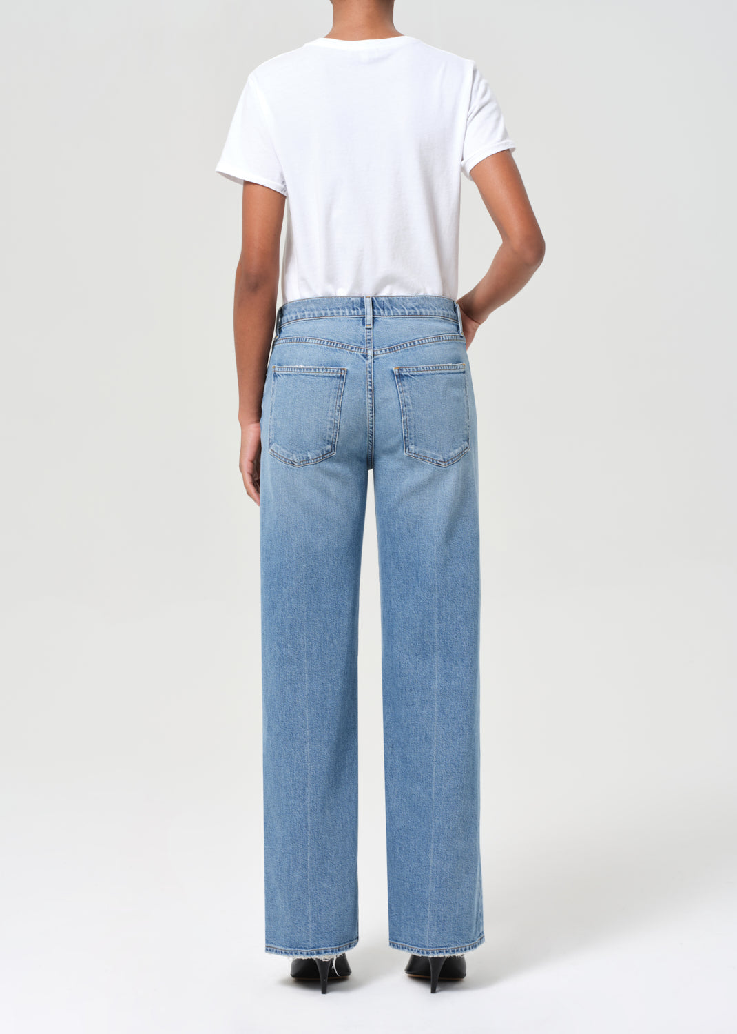 Person wearing light blue jeans and a white t-shirt on a white background