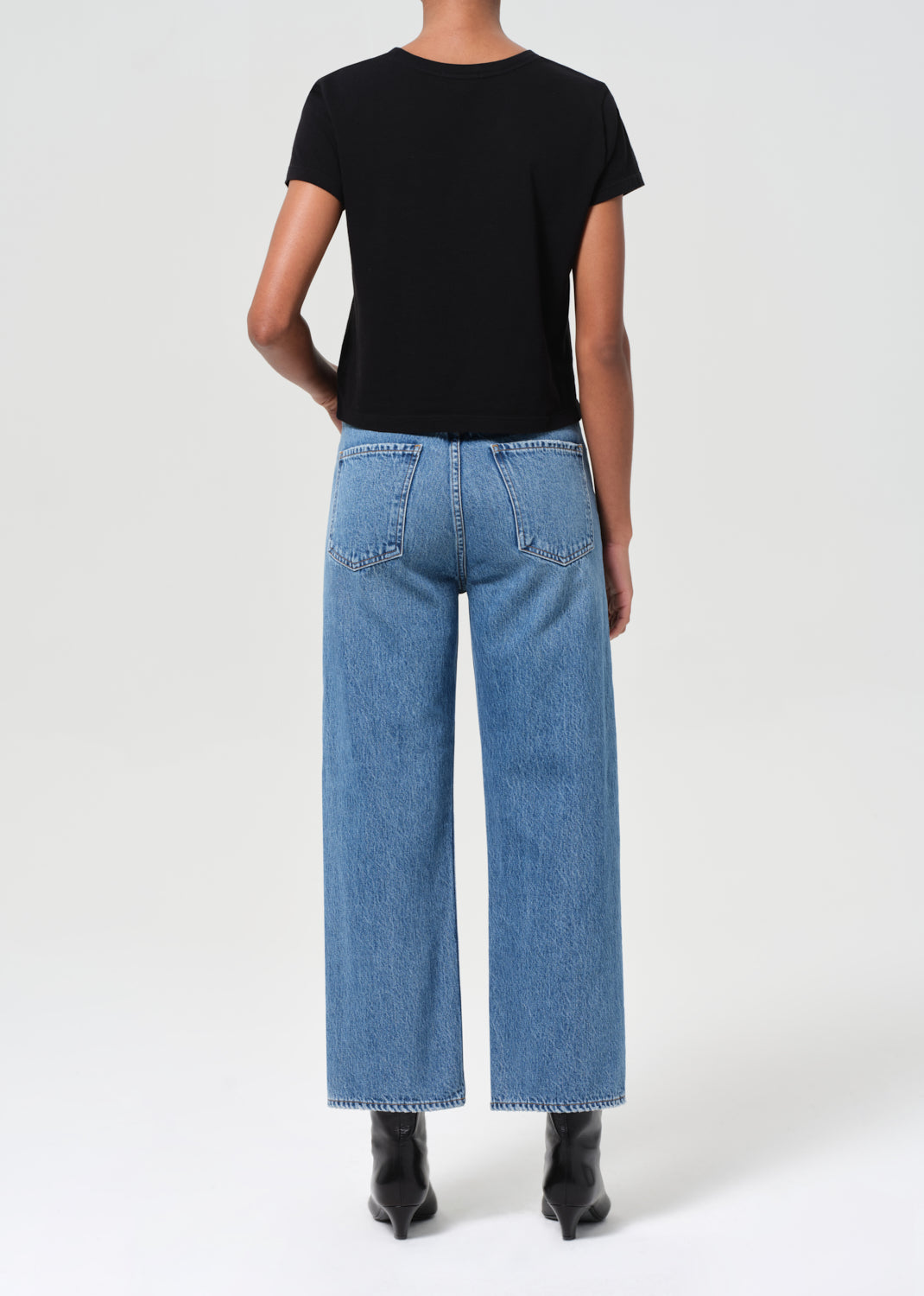 Person wearing a black t-shirt and blue jeans on a white background