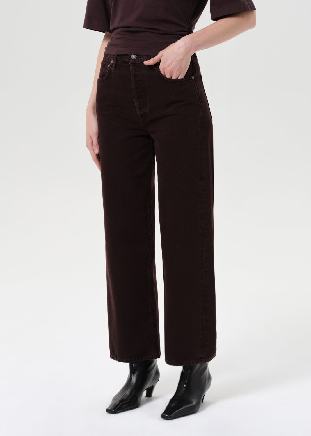 Person wearing dark brown pants and black shoes on a white background