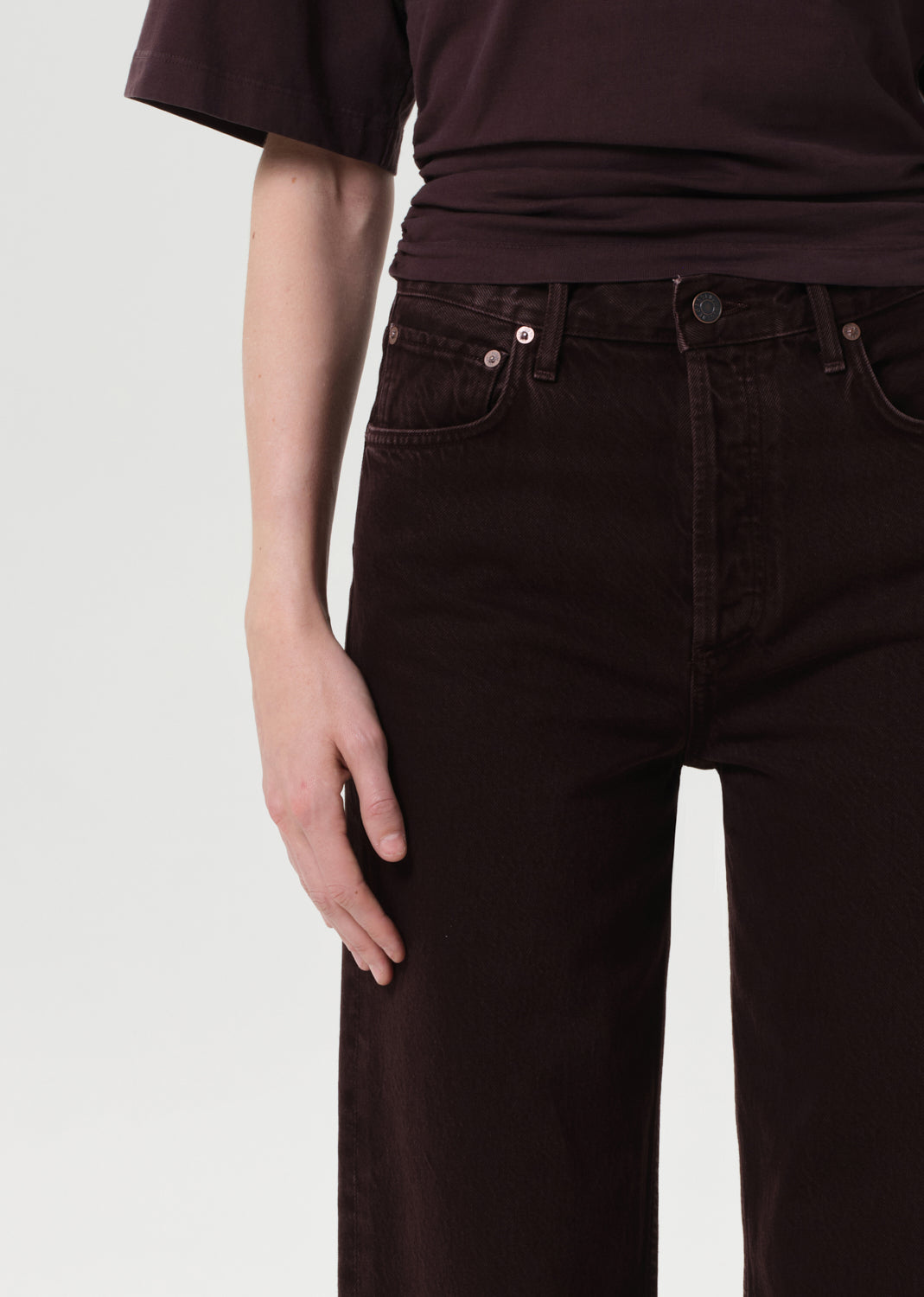 Person wearing dark brown pants and shirt on a white background