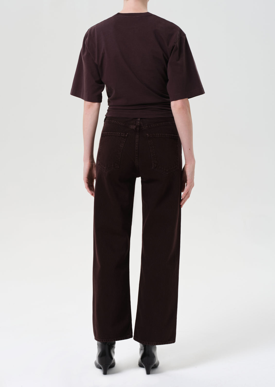 Person wearing a brown t-shirt and wide-leg pants on a white background