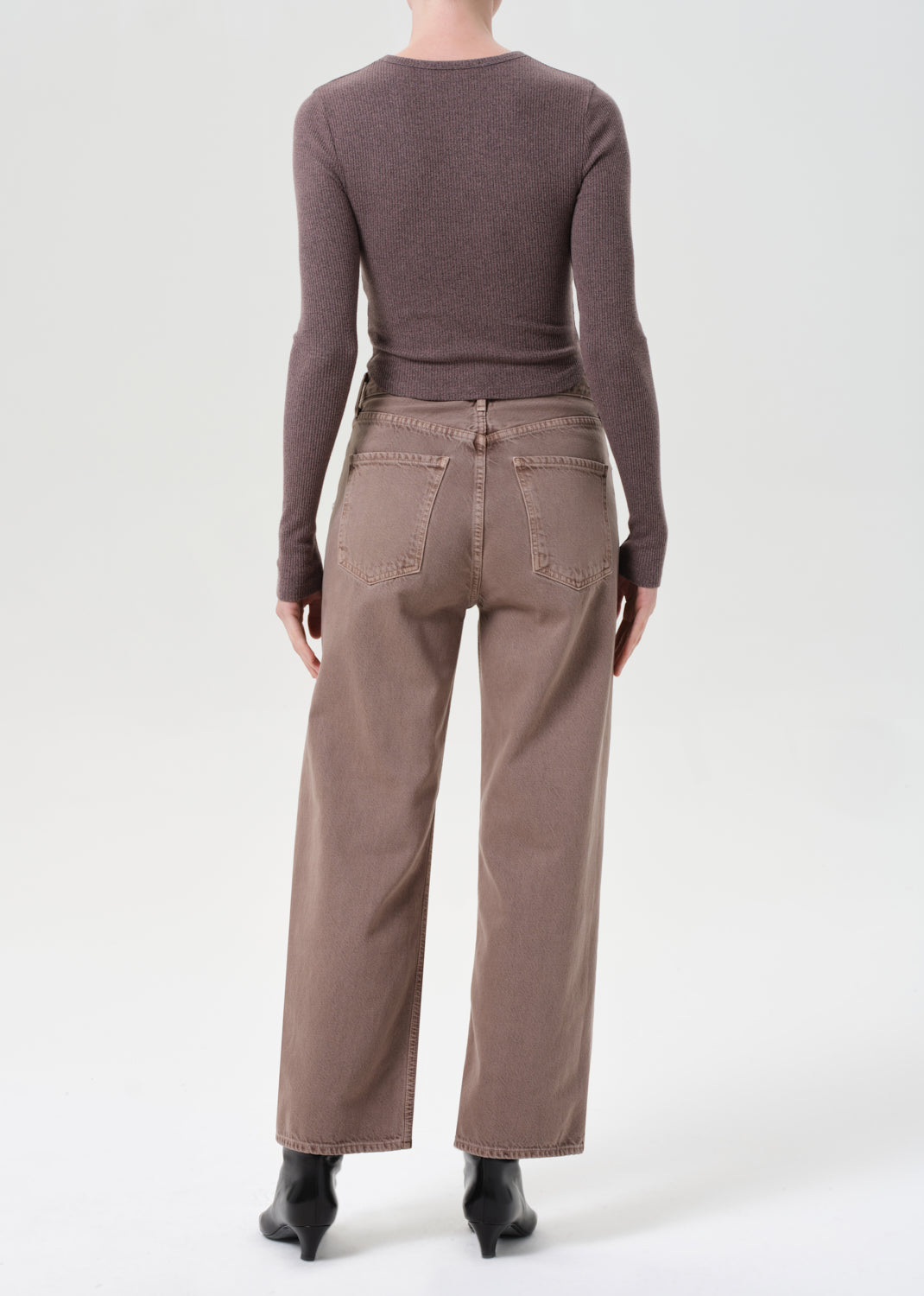 Person wearing a brown sweater and pants on a white background