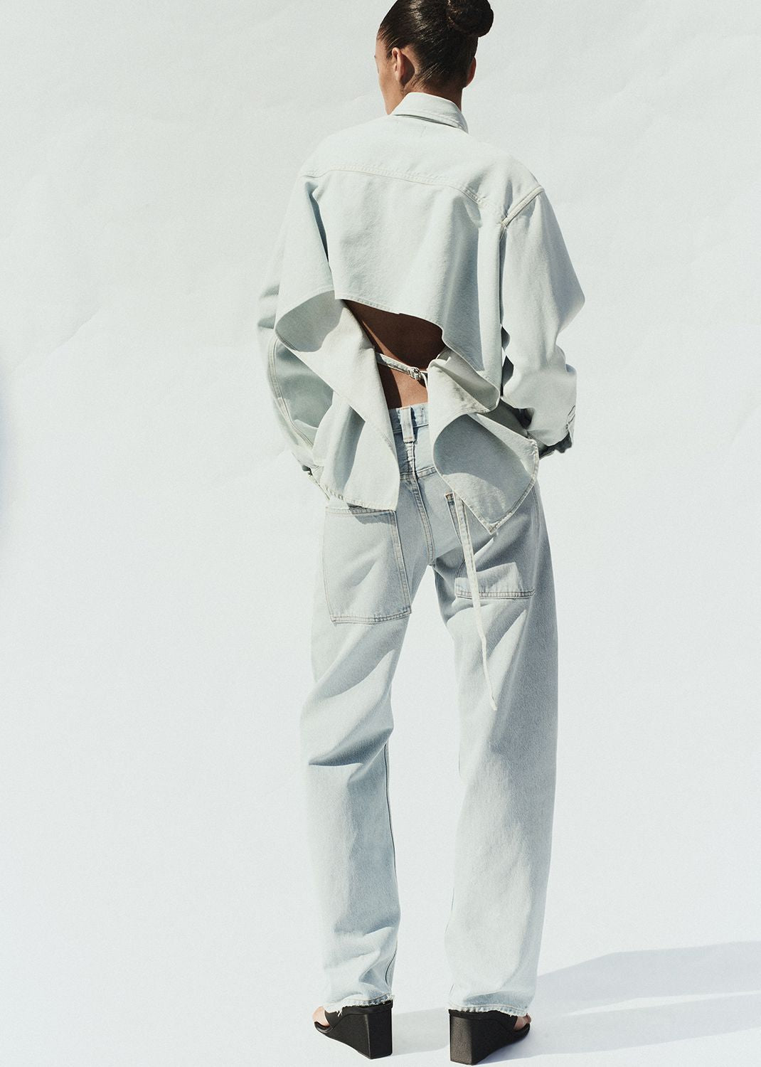 Person wearing a light gray outfit with a cutout design on a white background