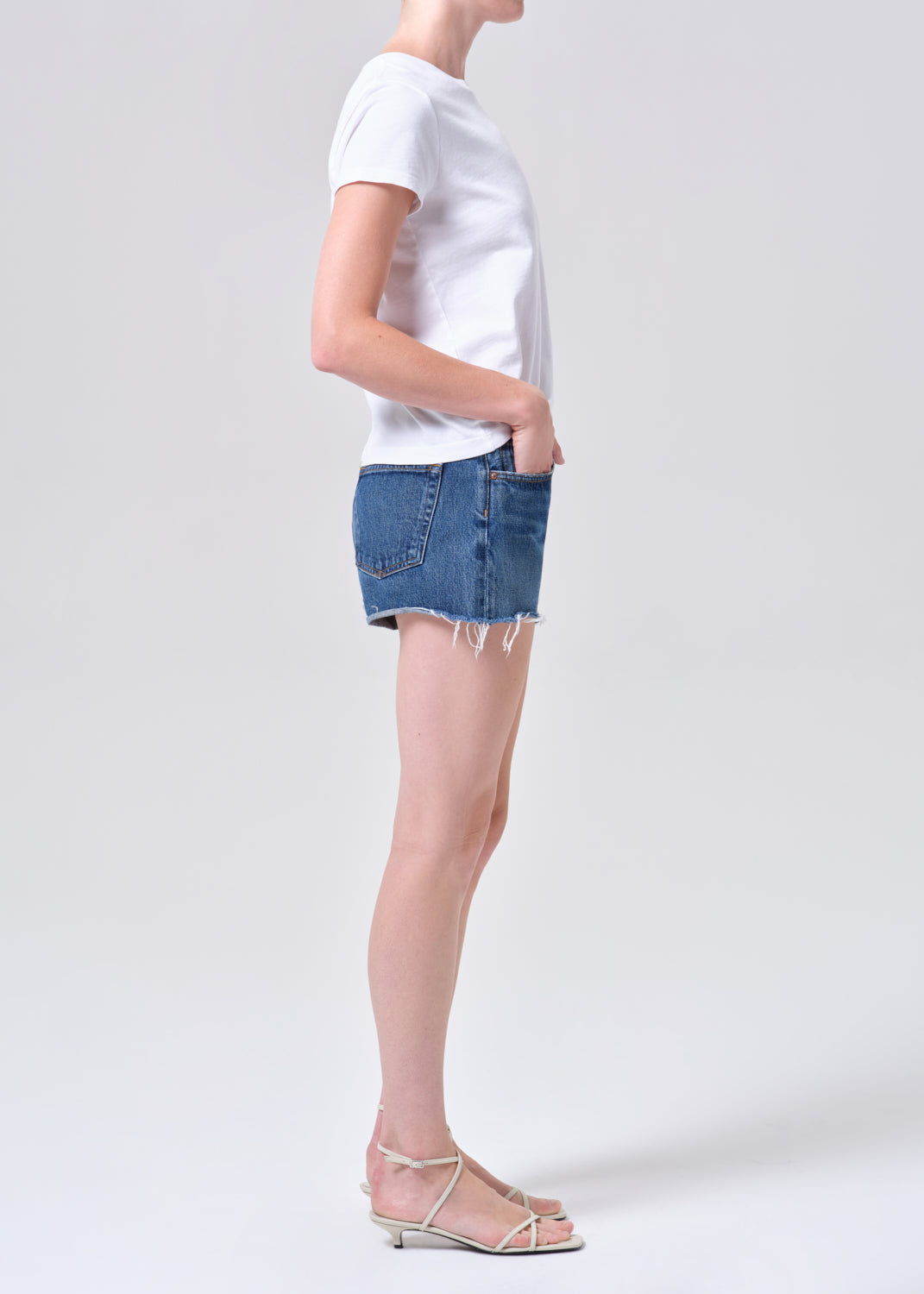 Person wearing a white t-shirt and denim skirt on a plain background