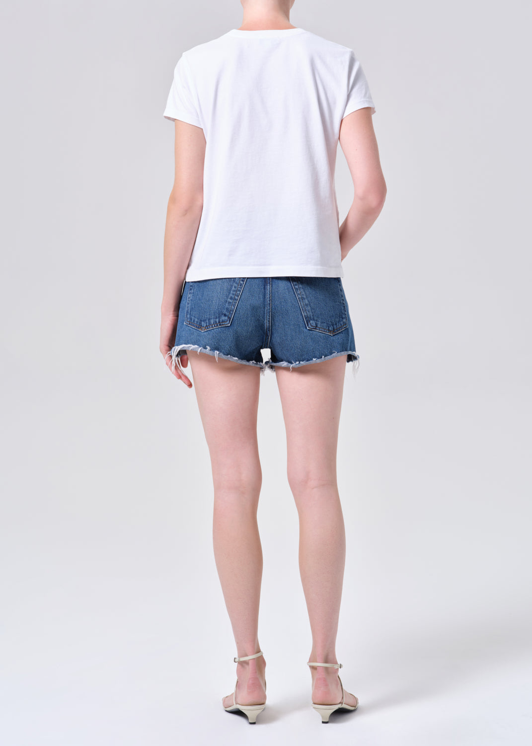 Person wearing a white t-shirt and blue denim shorts on a white background