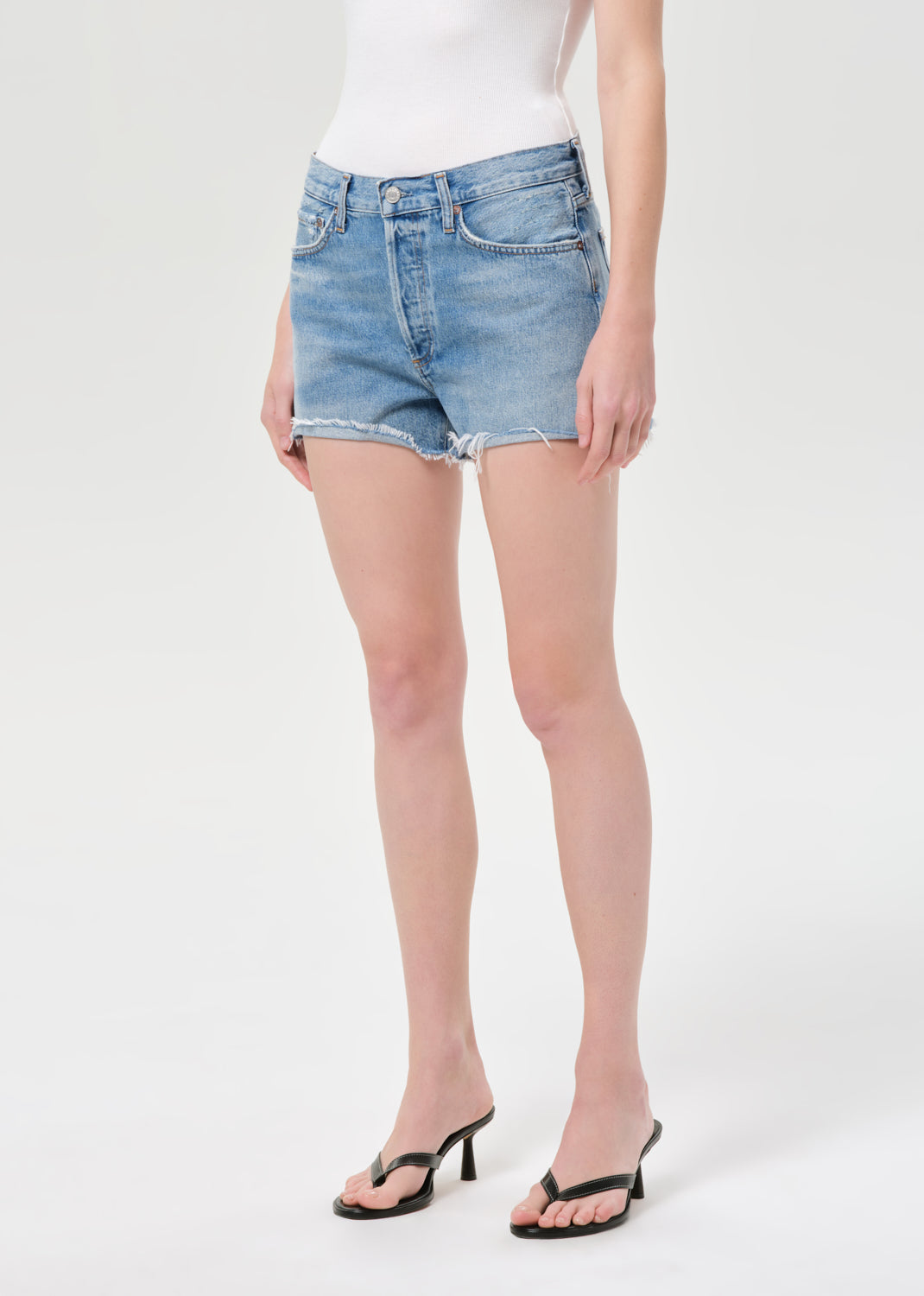 Person wearing light blue denim shorts on a white background
